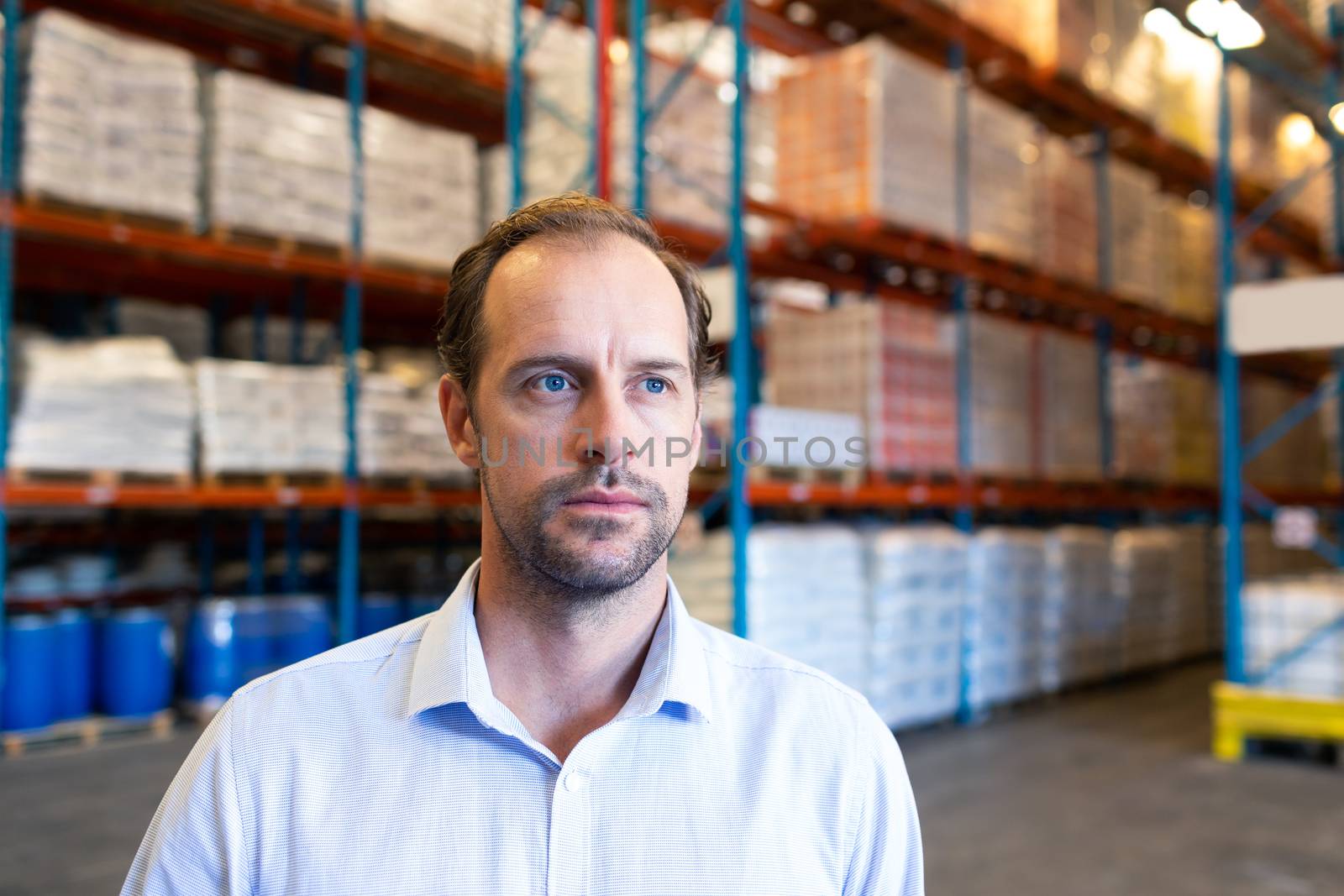 Portrait close-up of handsome mature Caucasian male supervisor looking away in warehouse. This is a freight transportation and distribution warehouse. Industrial and industrial workers concept