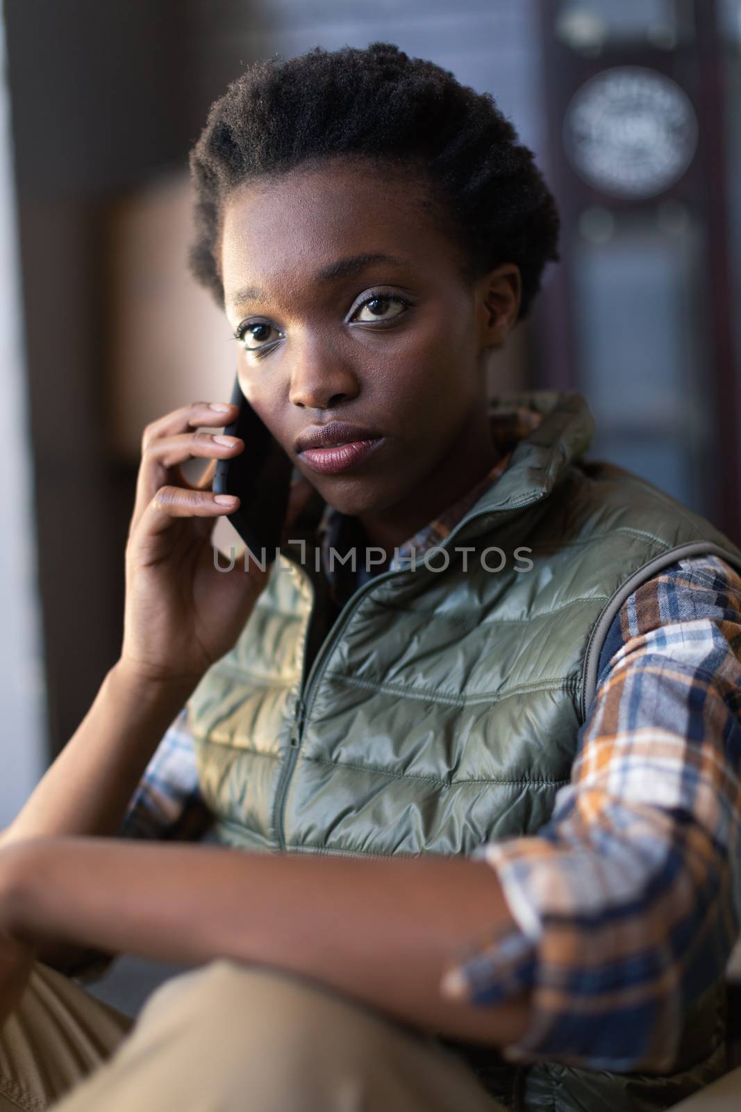 Close-up of African-american female worker talking on mobile phone in warehouse. This is a freight transportation and distribution warehouse. Industrial and industrial workers concept