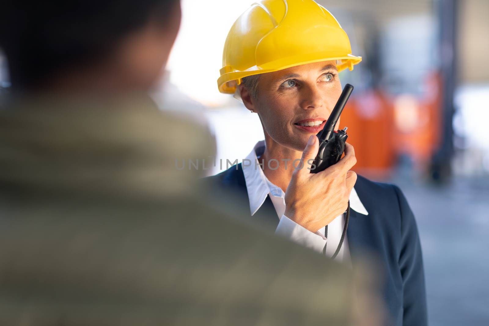 Female manager talking on walkie talkie in warehouse by Wavebreakmedia