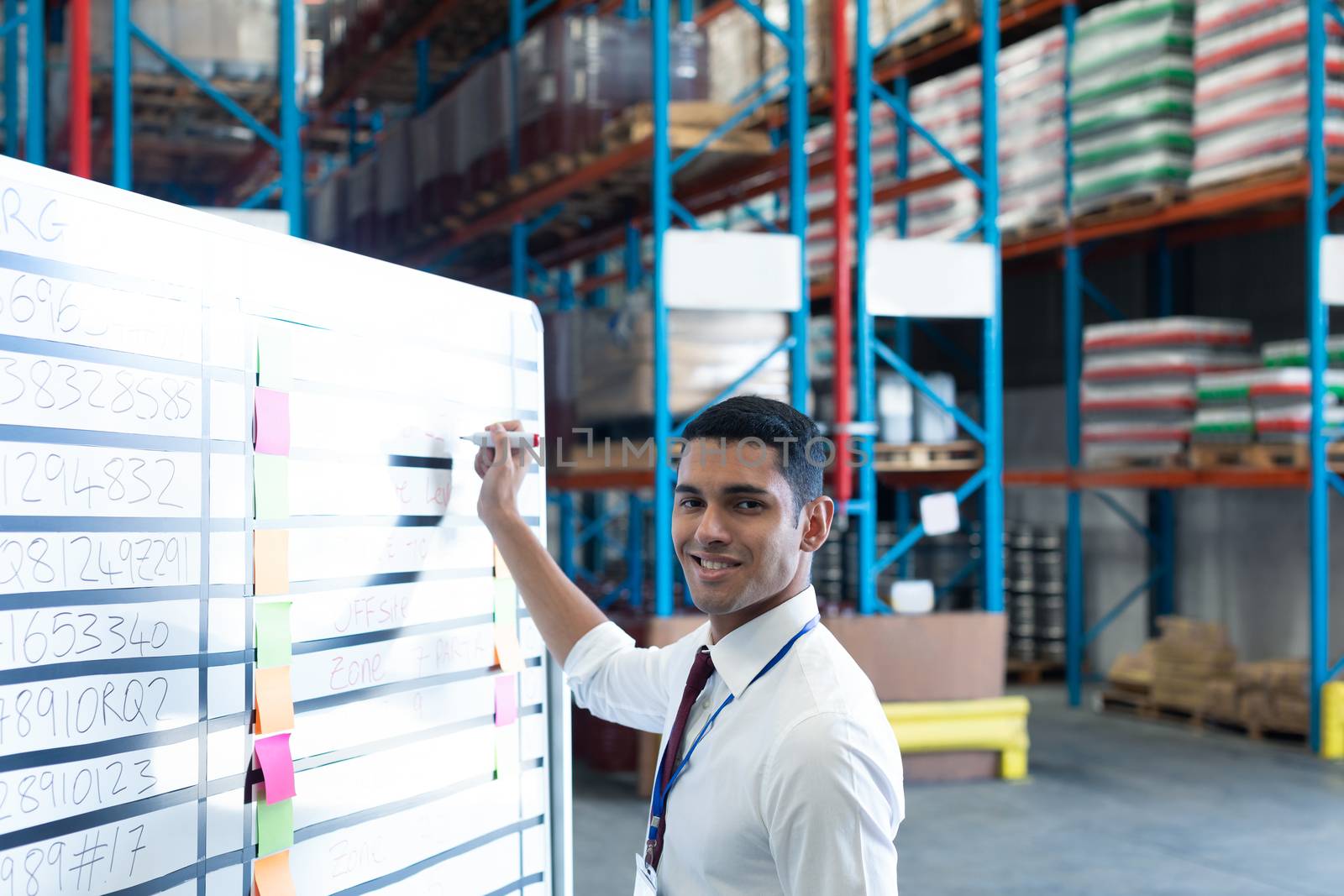 Male supervisor writing on whiteboard in warehouse by Wavebreakmedia