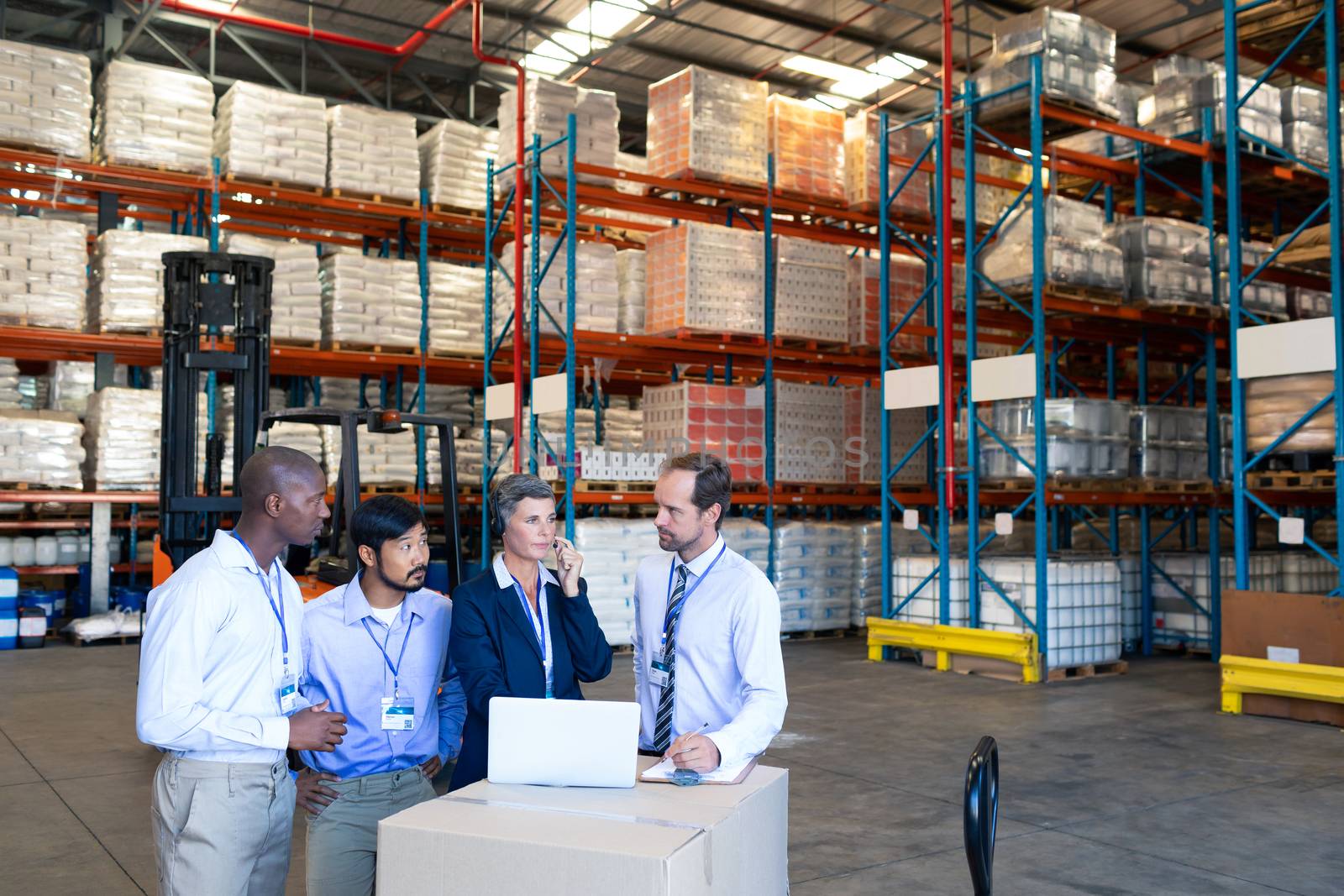 Front view of diverse staff discussing with each other in warehouse. This is a freight transportation and distribution warehouse. Industrial and industrial workers concept