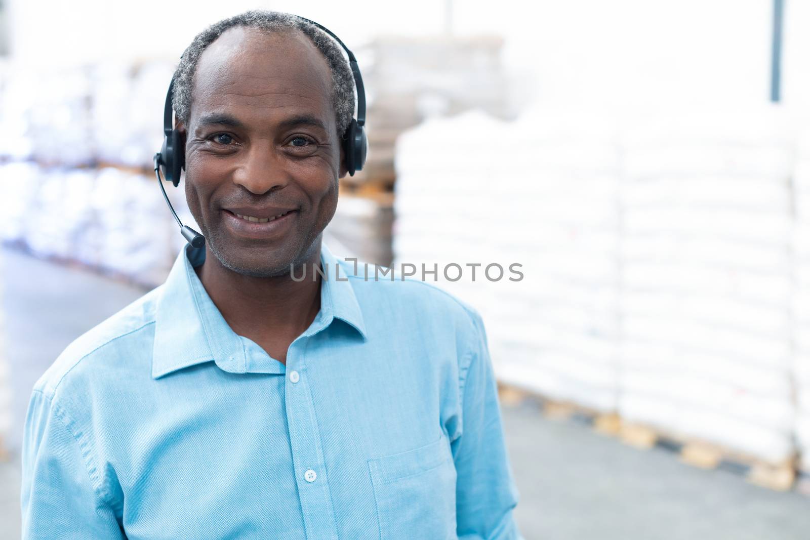 Male supervisor with headset standing in warehouse by Wavebreakmedia