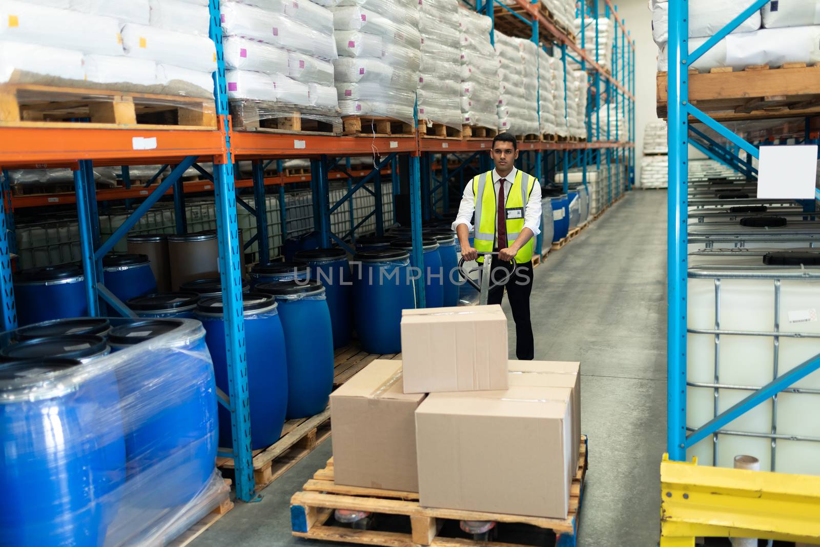 Front view of Caucasian male staff using pallet jack in warehouse. This is a freight transportation and distribution warehouse. Industrial and industrial workers concept