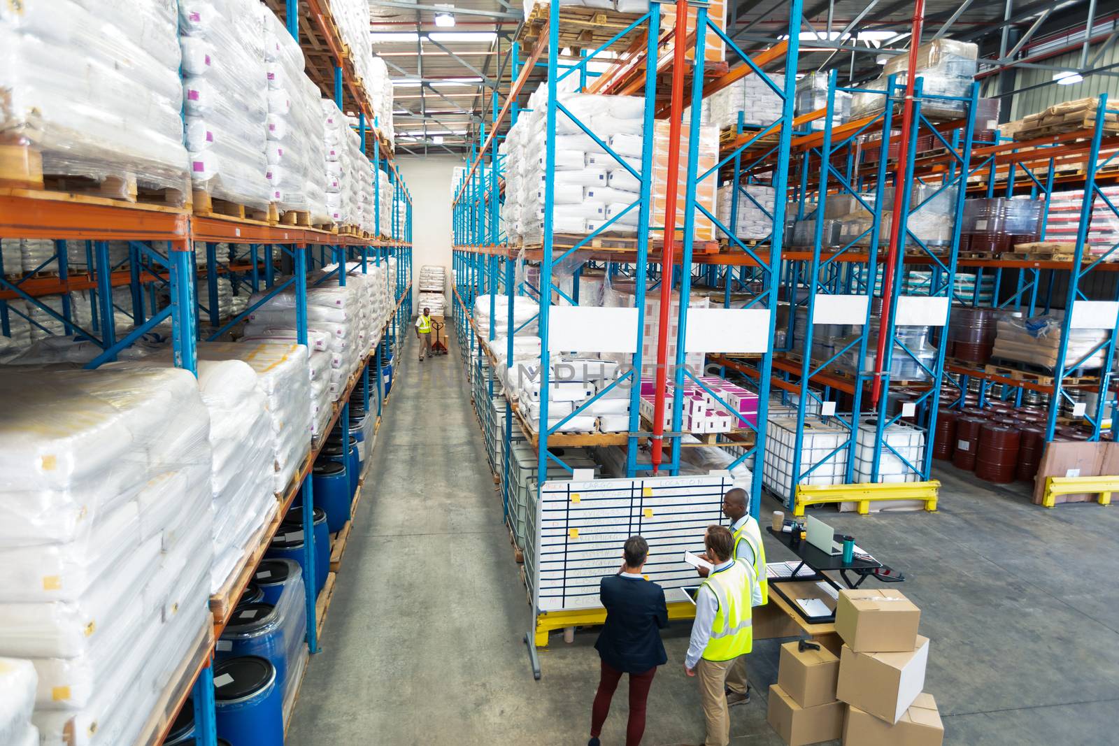 Warehouse staff discussing over whiteboard in warehouse by Wavebreakmedia