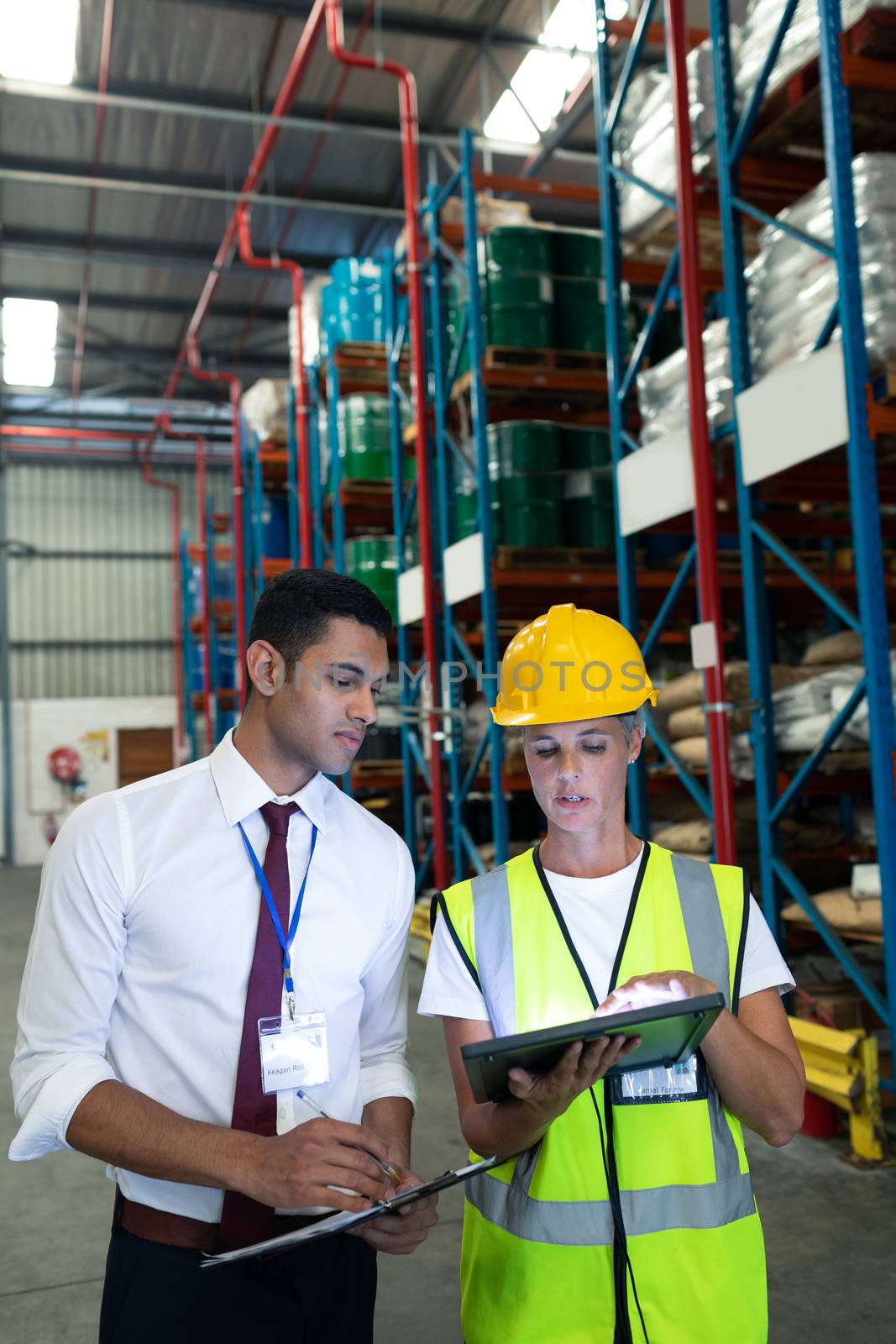 Front view of diverse Attentive warehouse staffs discussing over digital tablet in warehouse. This is a freight transportation and distribution warehouse. Industrial and industrial workers concept