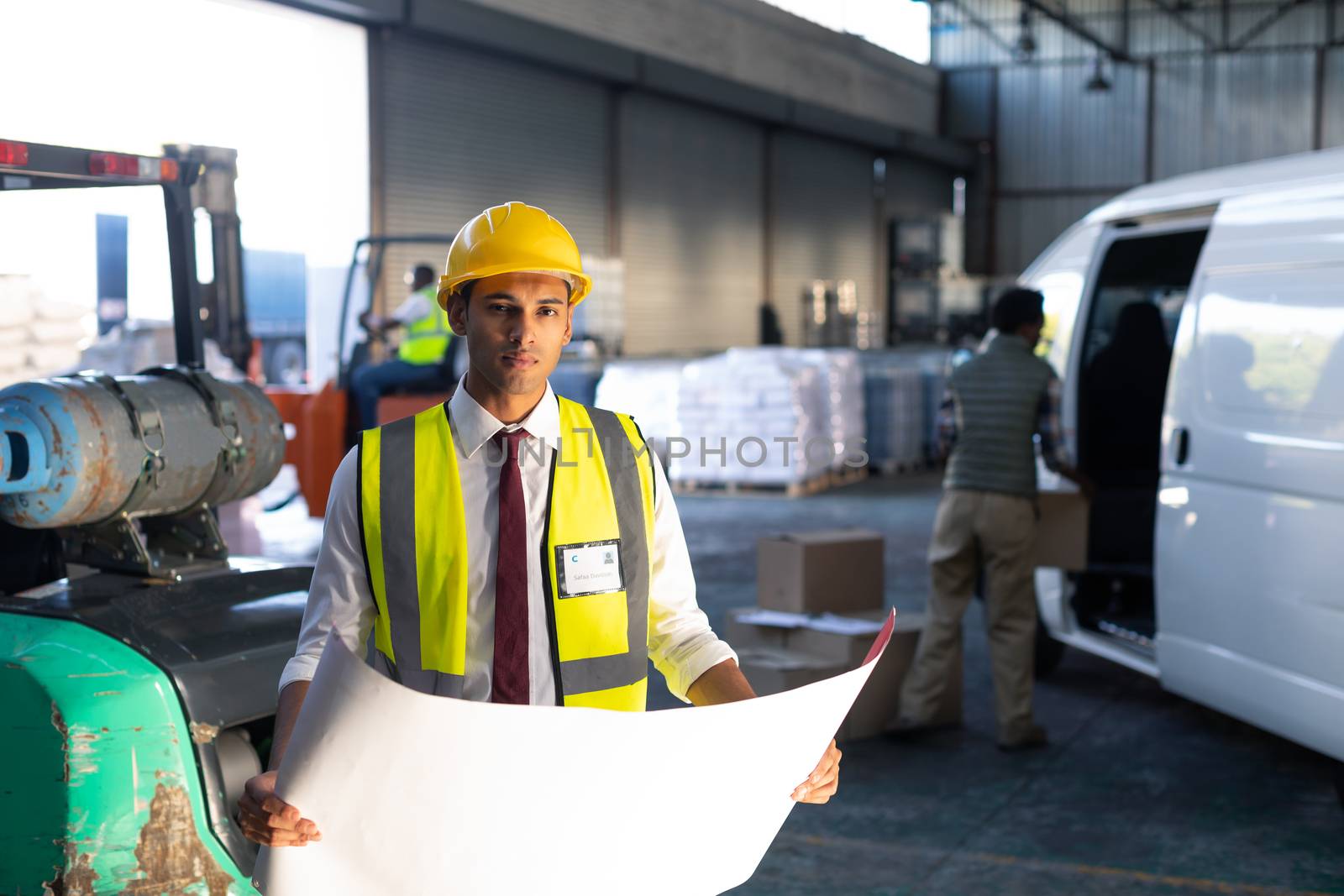 Portrait of young Caucasian male supervisor looking at blueprint in warehouse. This is a freight transportation and distribution warehouse. Industrial and industrial workers concept