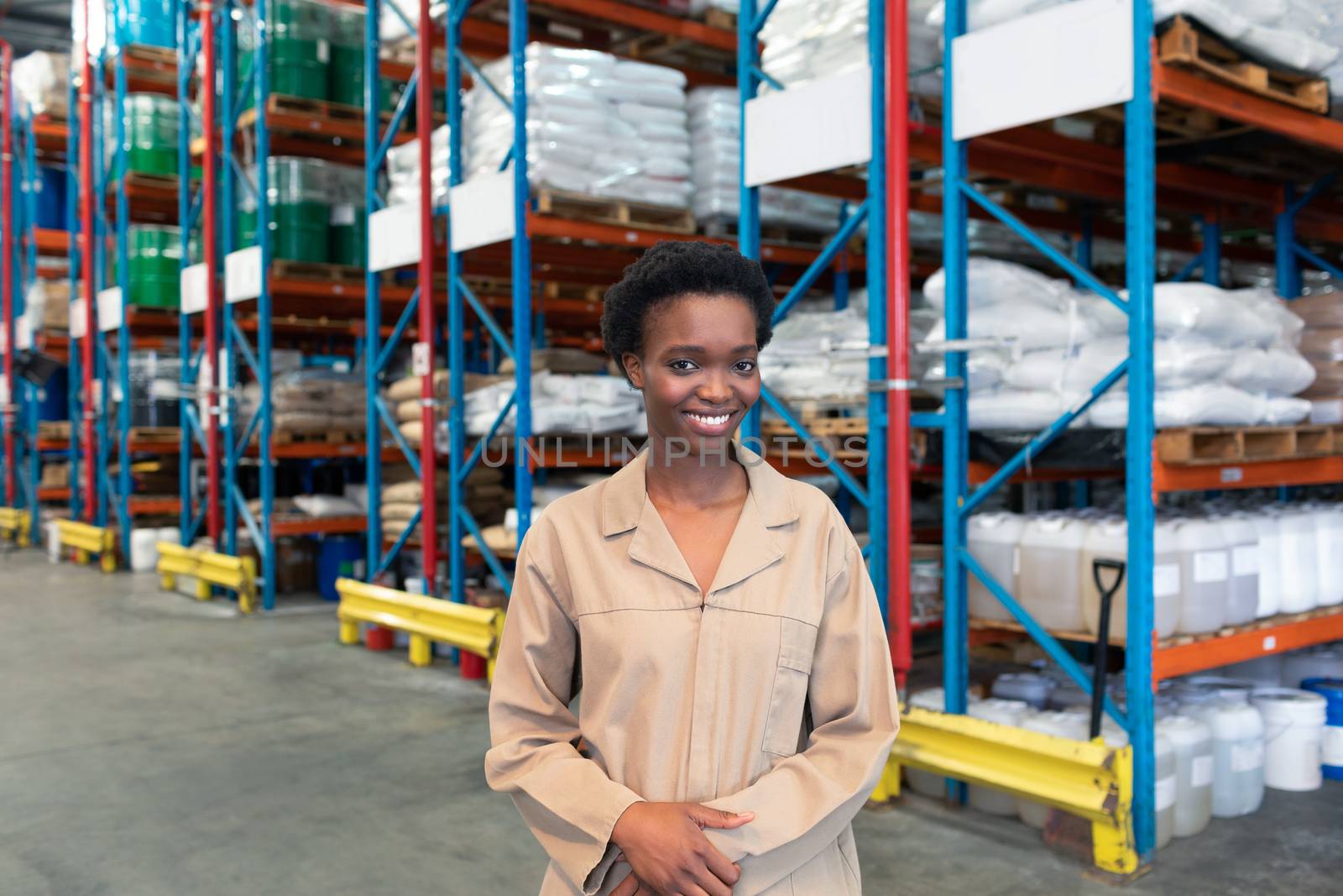 Portrait of happy young African-american female warehouse staff looking at camera. This is a freight transportation and distribution warehouse. Industrial and industrial workers concept