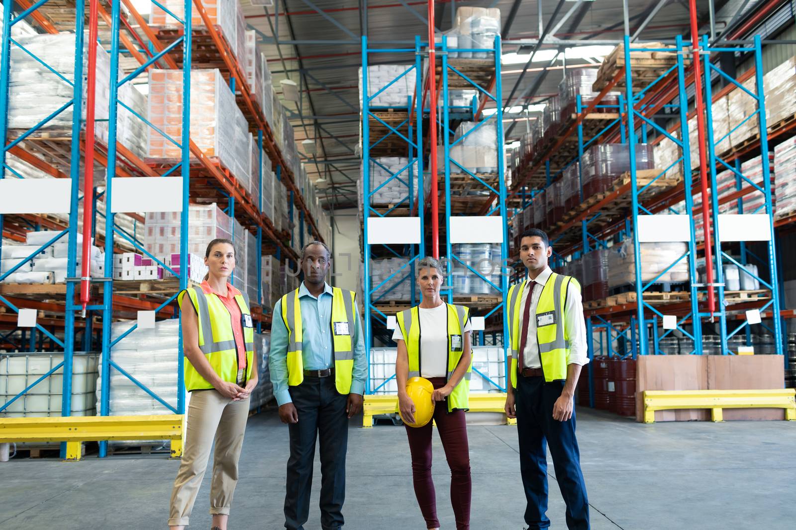 Front view of diverse warehouse staffs standing together in warehouse. This is a freight transportation and distribution warehouse. Industrial and industrial workers concept