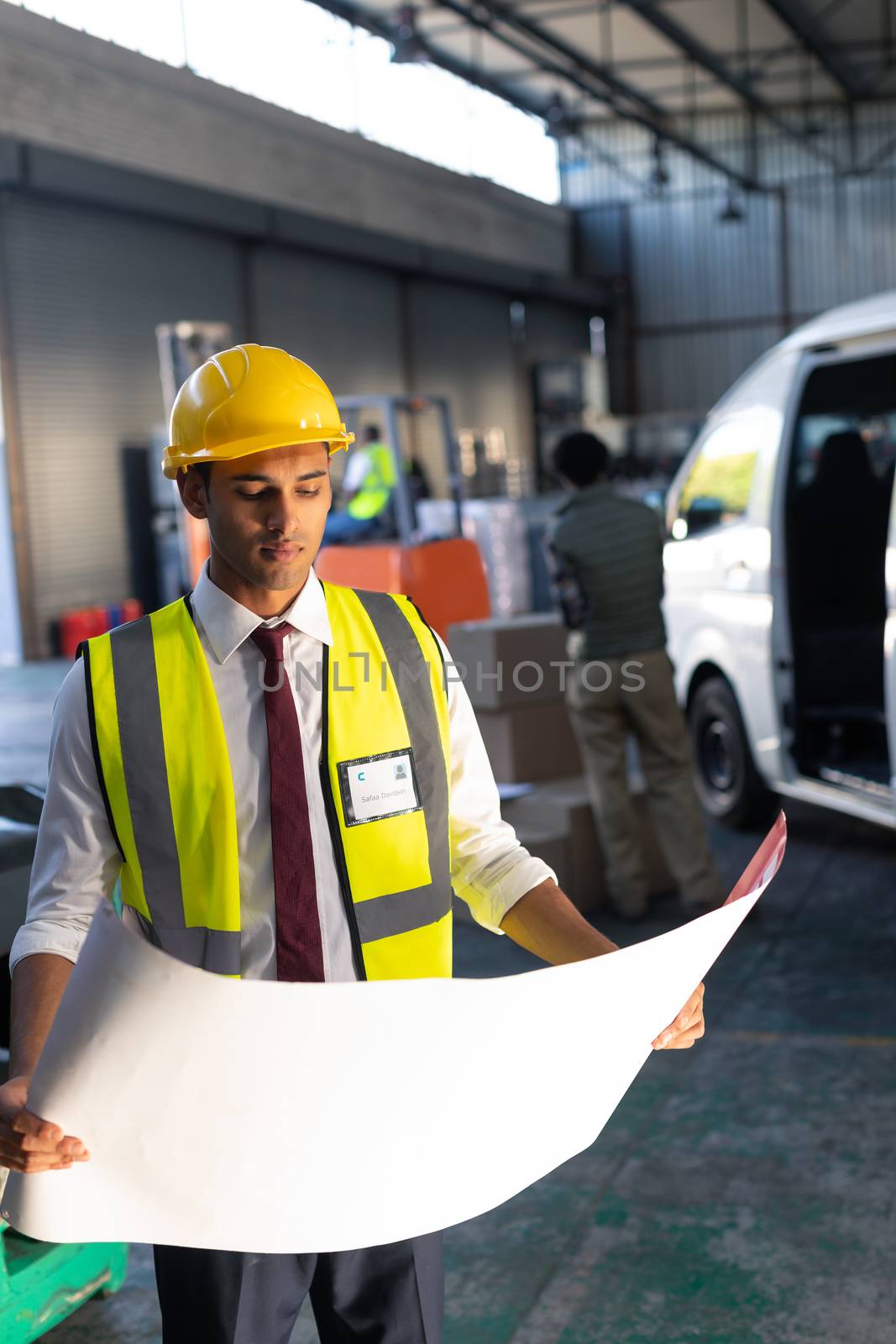 Front view of Caucasian male supervisor looking at blueprint in warehouse. This is a freight transportation and distribution warehouse. Industrial and industrial workers concept