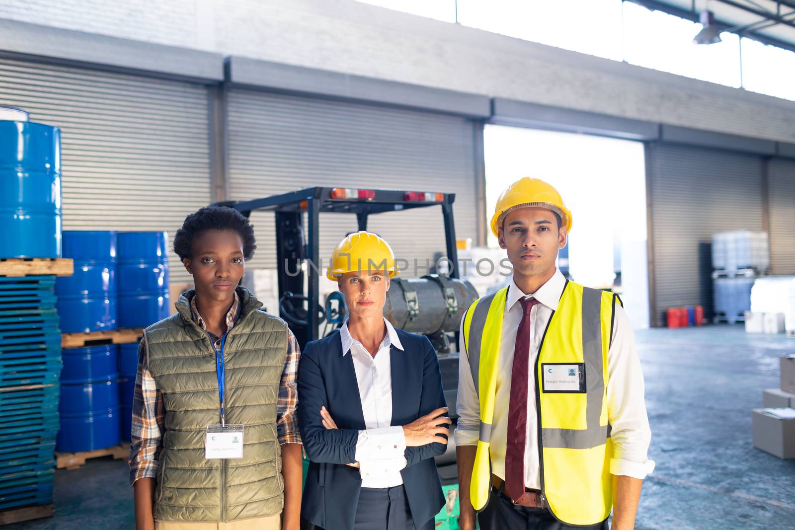 Front view of diverse warehouse staff looking at camera in warehouse. This is a freight transportation and distribution warehouse. Industrial and industrial workers concept