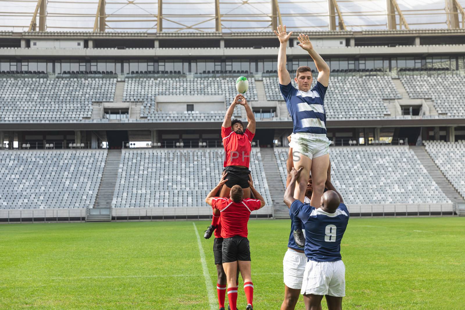 Male rugby players playing rugby match in stadium by Wavebreakmedia