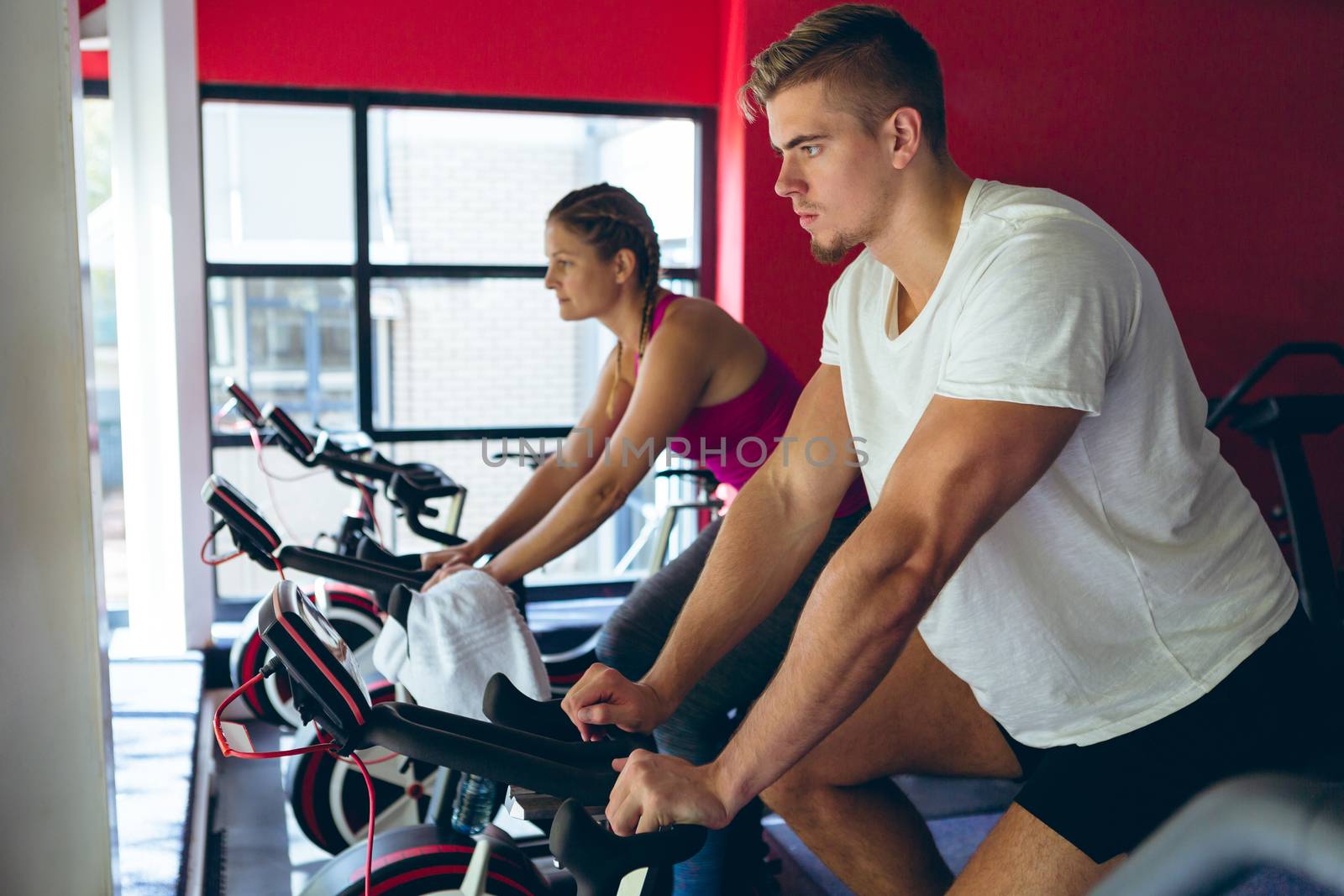 Male and female athlete exercising with exercise bike in fitness center by Wavebreakmedia