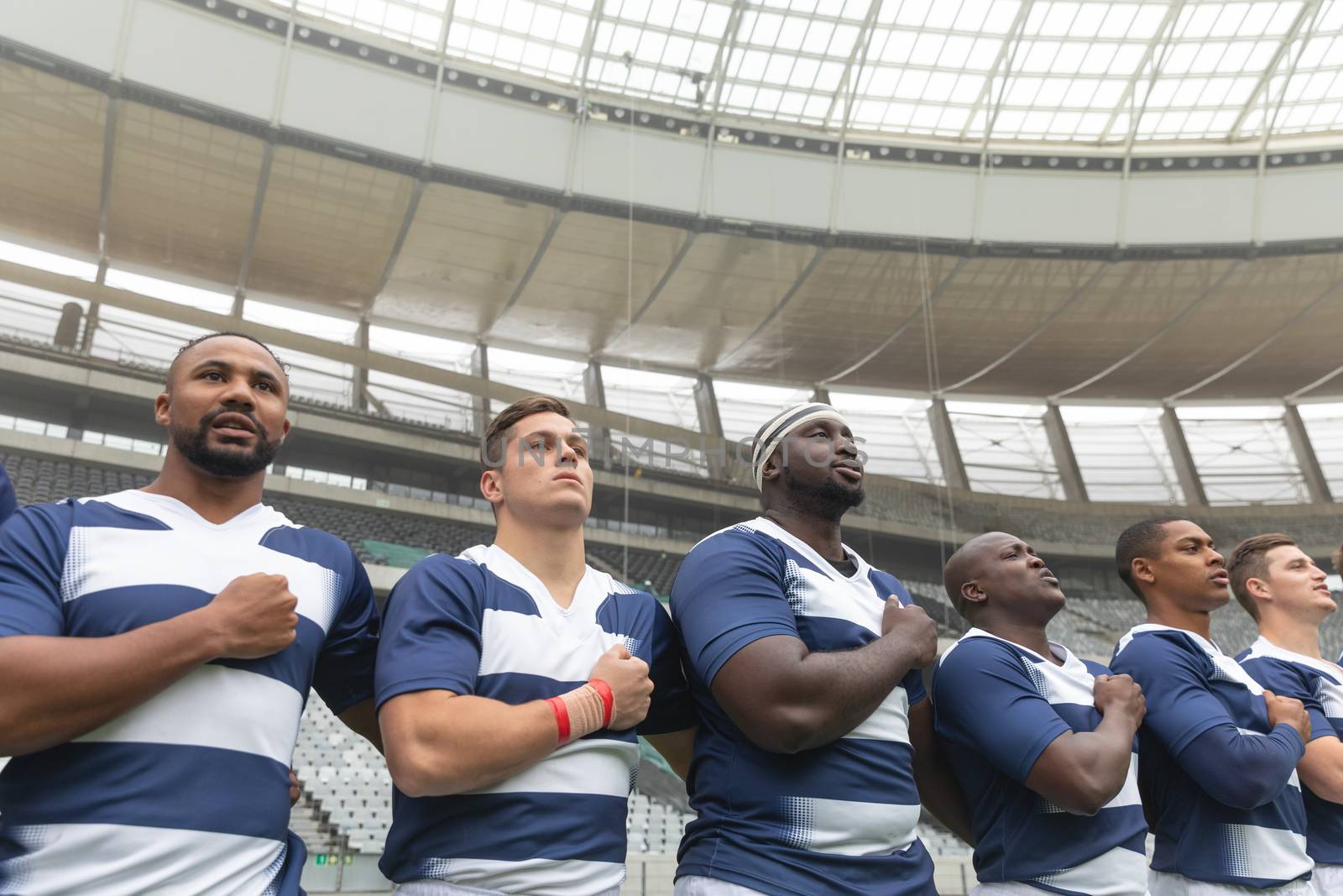 Group of diverse male rugby players taking pledge together in stadium by Wavebreakmedia