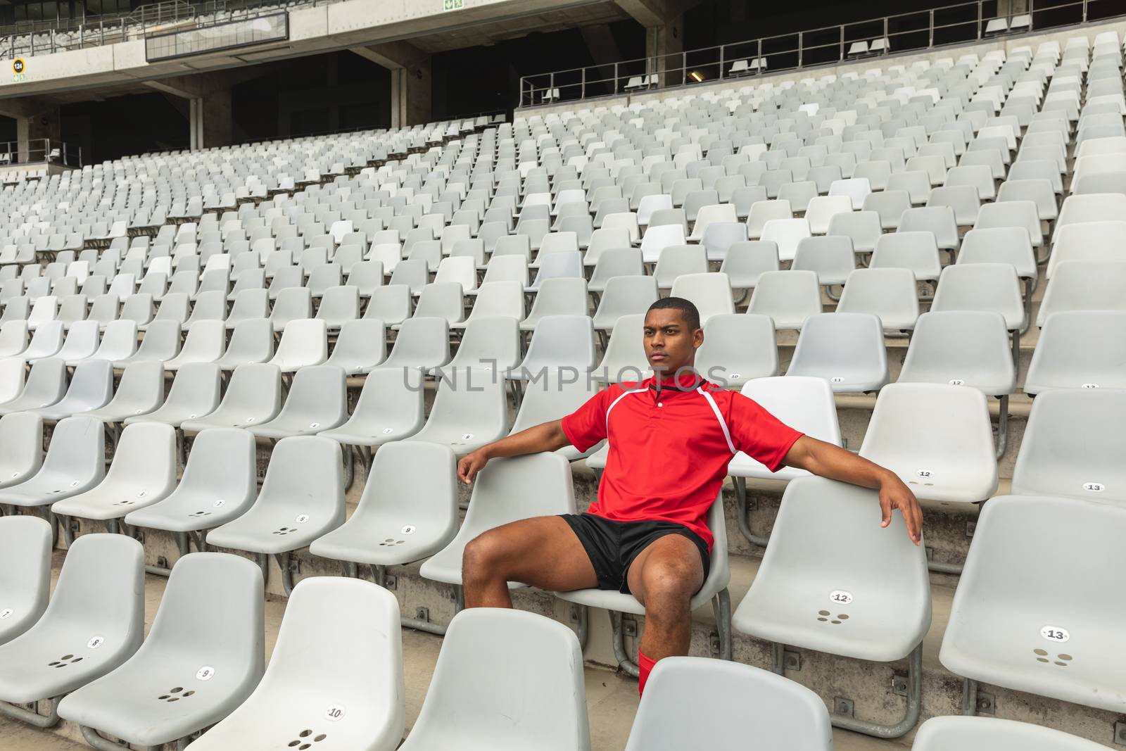 Side view of thoughtful African American male rugby player sitting alone in stadium