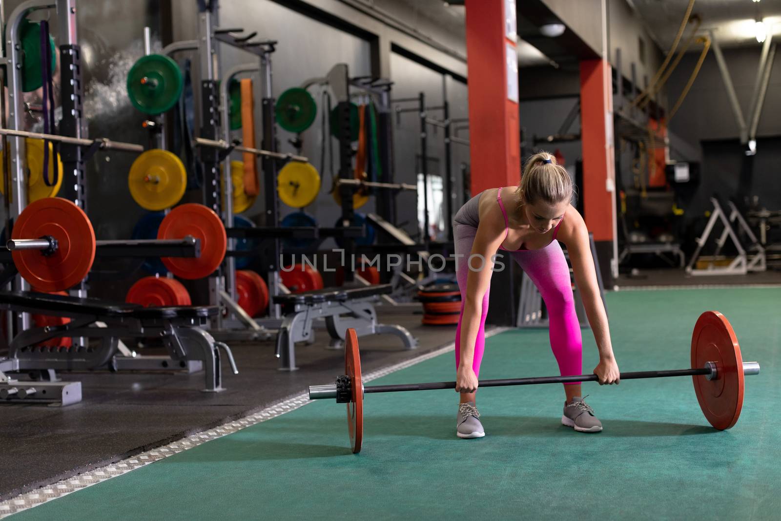 Front view of a Caucasian woman lifting weights inside a room at a sports centre. Bright modern gym with fit healthy people working out and training. Bright modern gym with fit healthy people working out and training