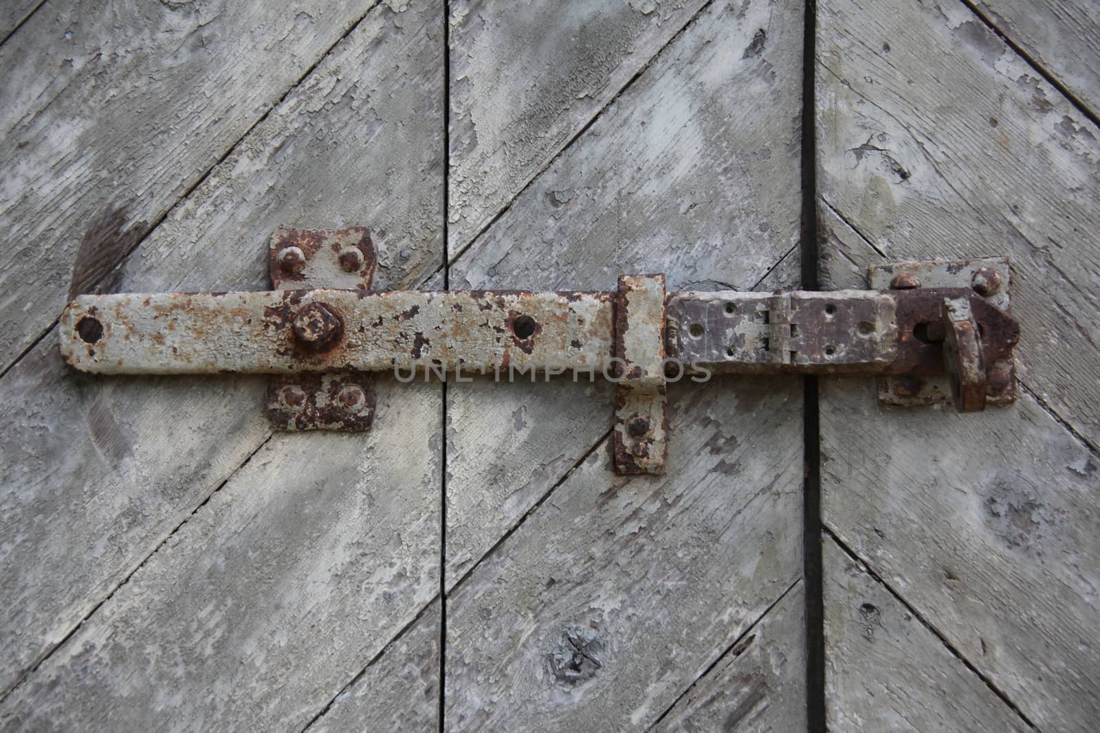 Old wooden door locked and latched outside.