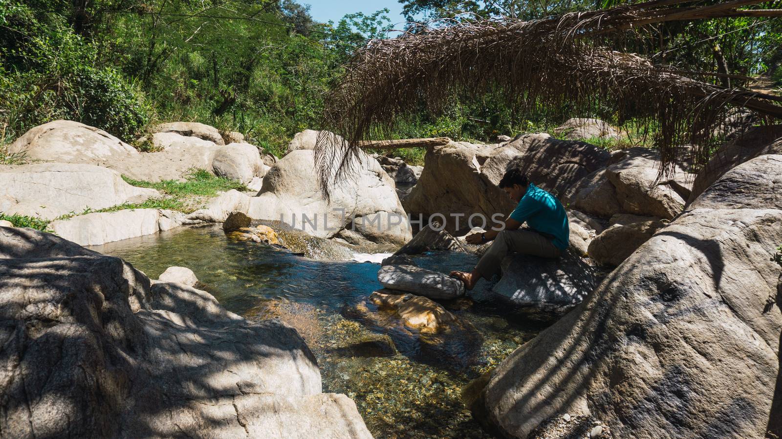 Man sitting in a rock and relaxing in the river