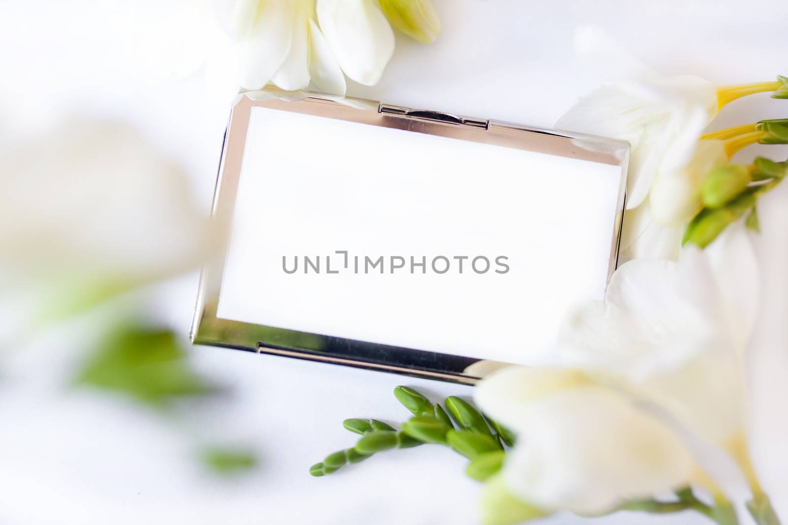 White freesia flowers and blank postcard on light background