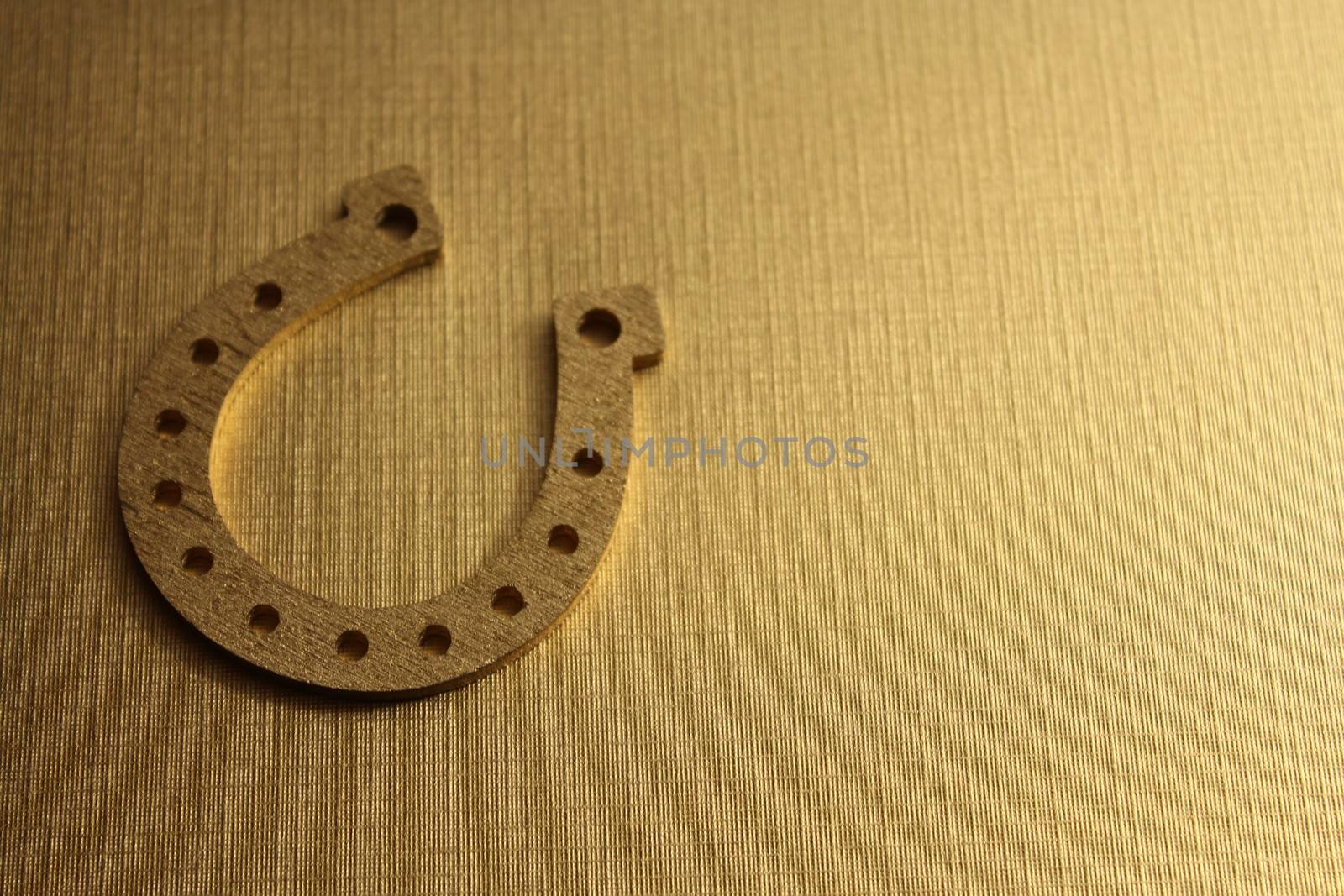 The picture shows a golden horseshoe on a golden background