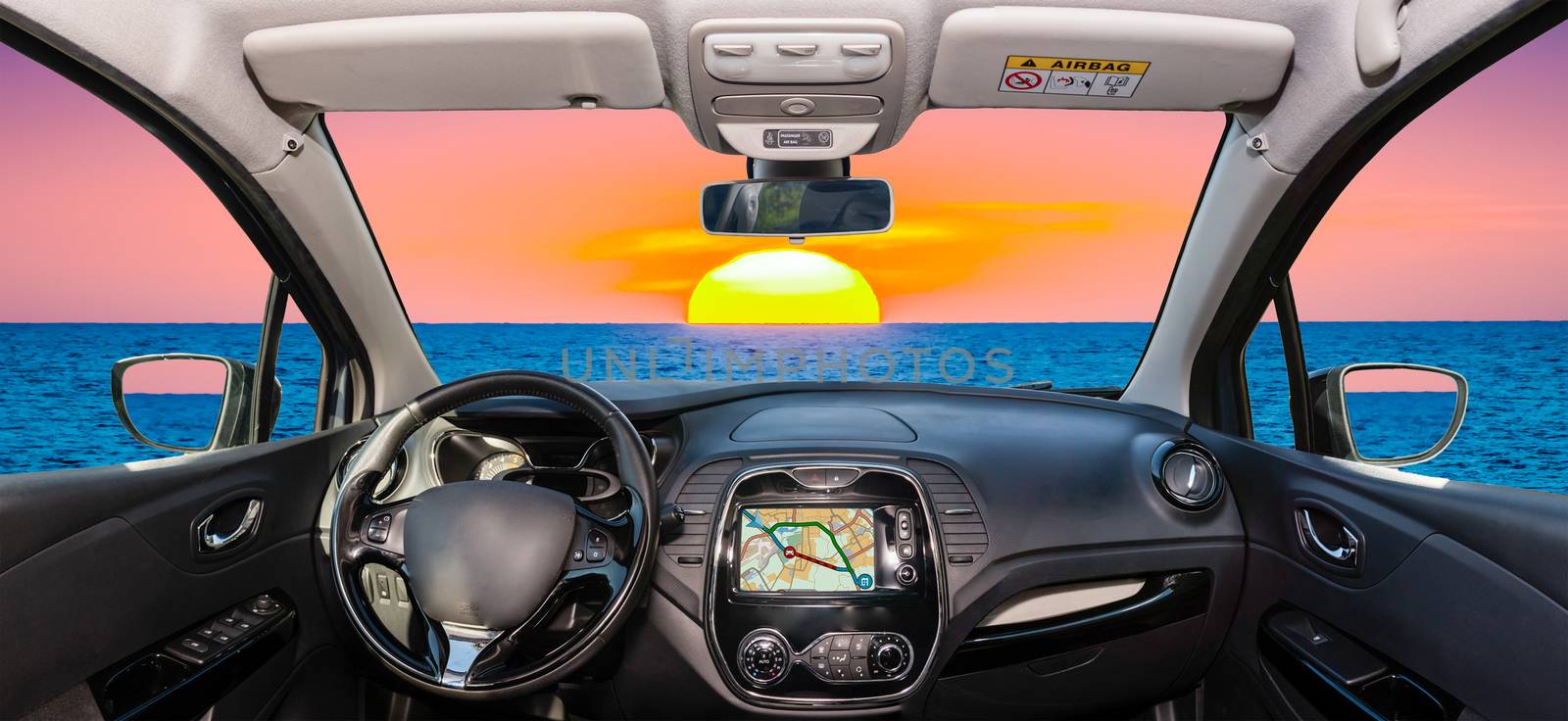 Looking through a car windshield with view of a beautiful sunset by the mediterranean sea, Italy