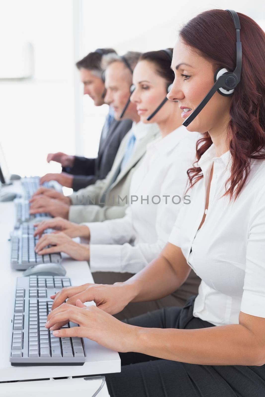 Employees typing on their computers using headsets