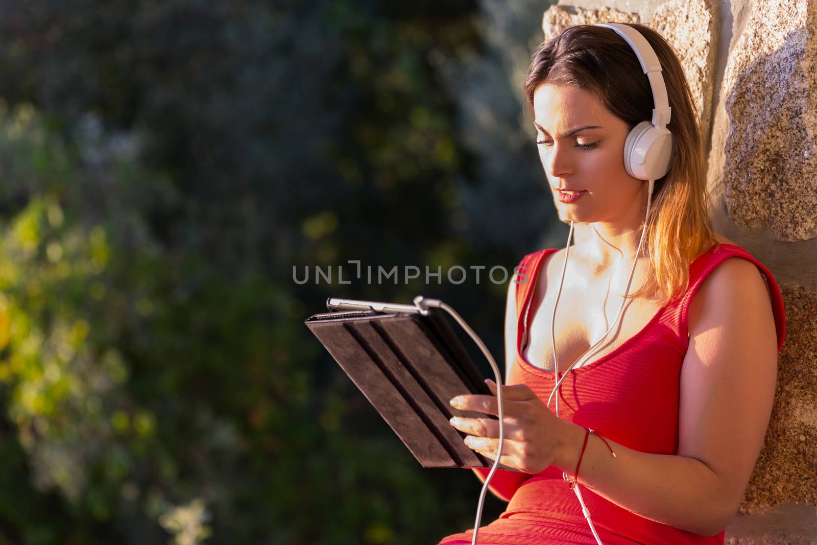 casual woman working with a tablet pc, with headphones, outdoor