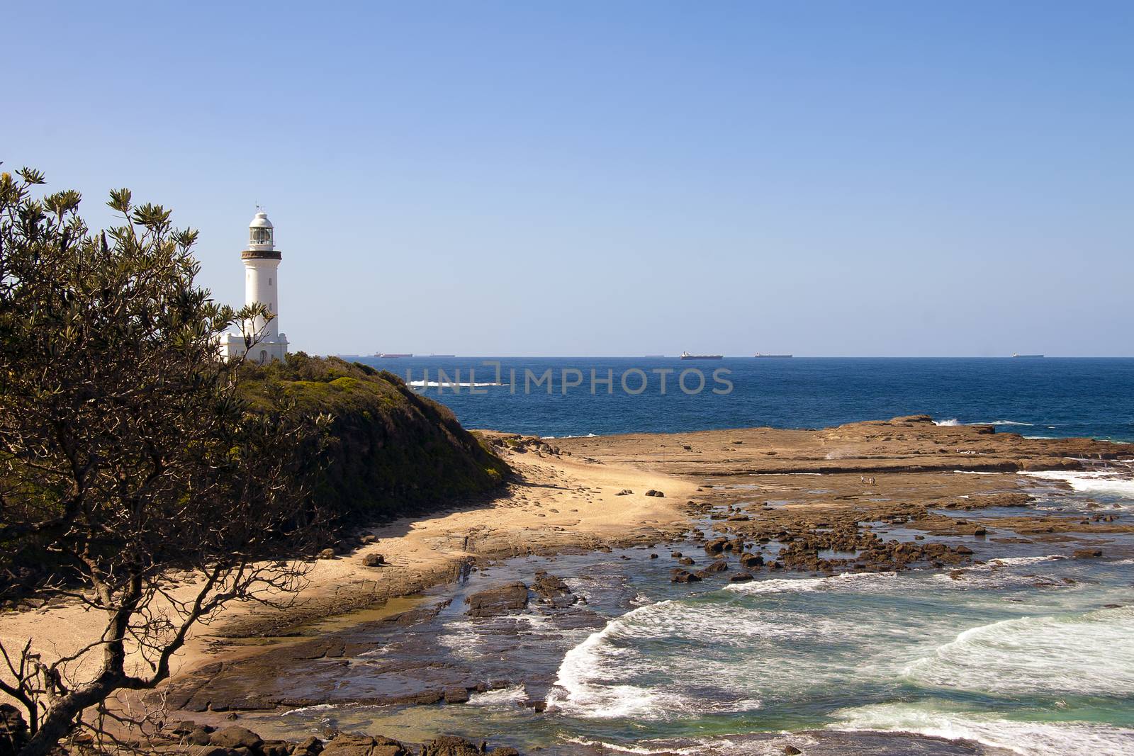 Lighthouse above an ocean swept rock platform by definitearts