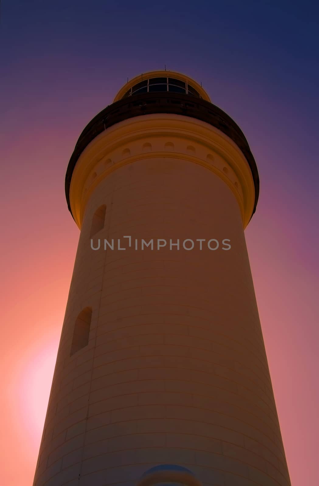 A lighthouse against the evening sunset by definitearts