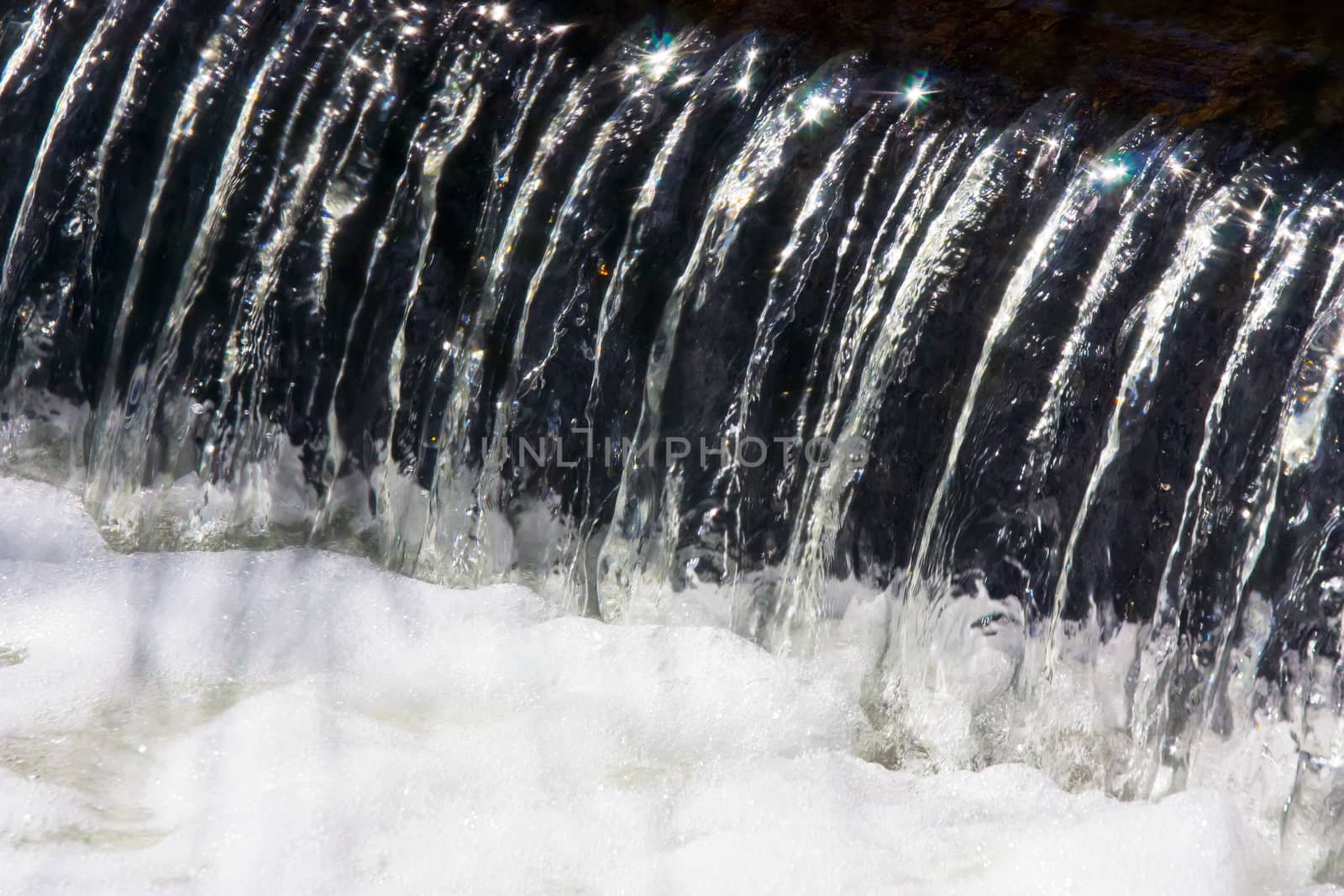 Closeup shot water flowing into a pool of foam by definitearts