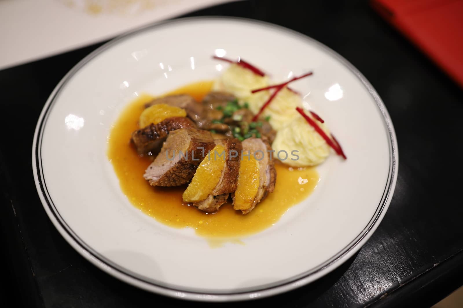 Roasted duck topped with orange sauce and mashed potatoes Decorate the dish looks appetizing on the white plate in the restaurant. Selective focus.