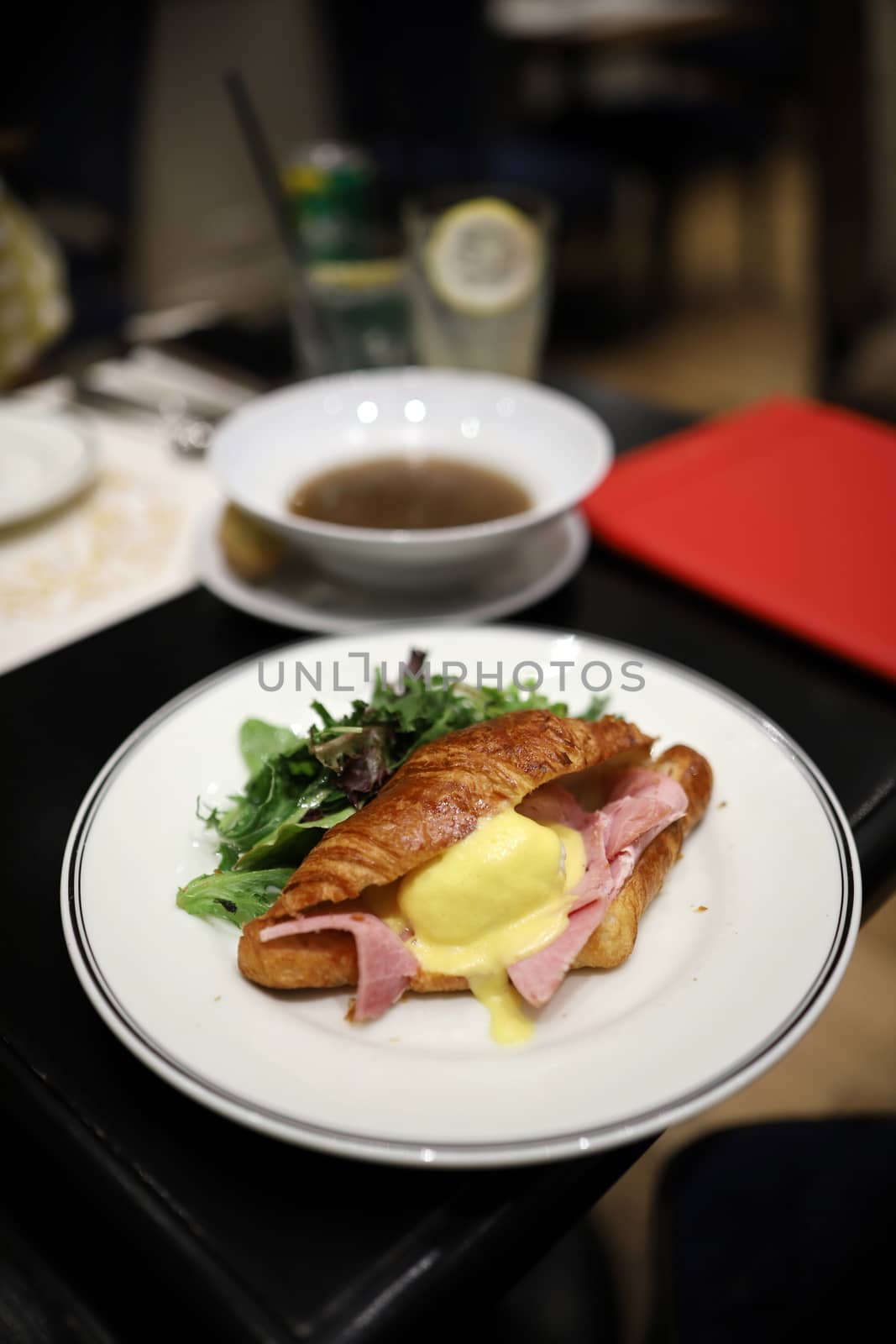 Croissants with eggs benedict and ham filling look appetizing on a white dish in a restaurant. Selective focus. by joker3753