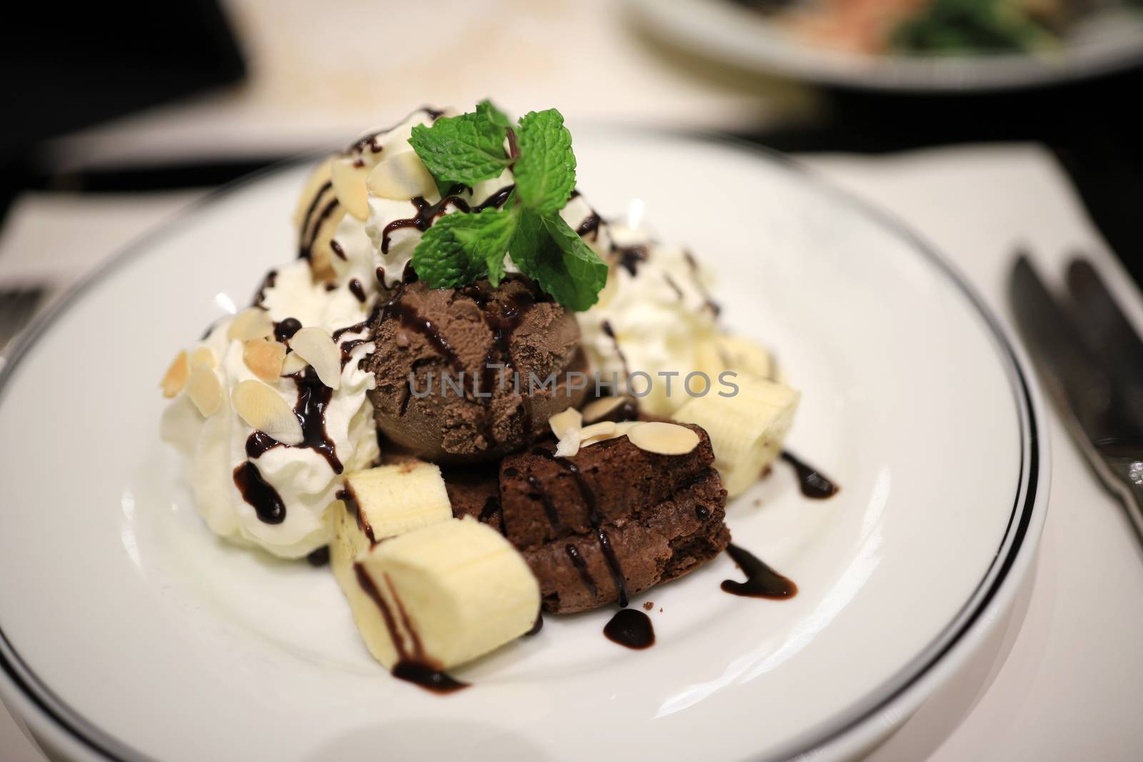 Chocolate ice cream and sliced bananas Garnish with mint leaves. With white mousse and sliced almonds in a white plate Topped with chocolate sauce to look delicious. Selective focus. by joker3753