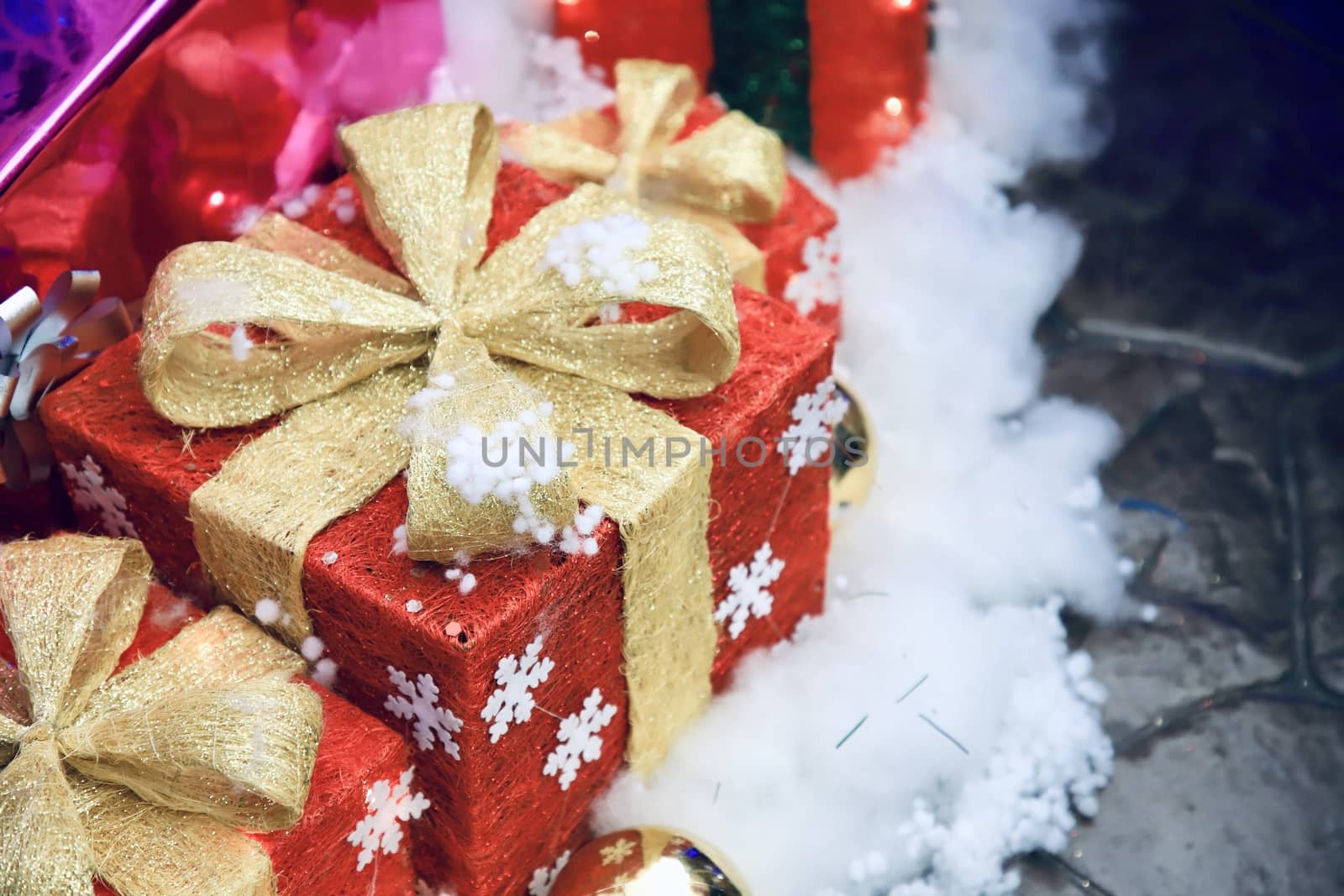 A red gift box with a golden bow on a white cotton floor For decorating the New Year's venue There is space to put text. Selective focus. by joker3753