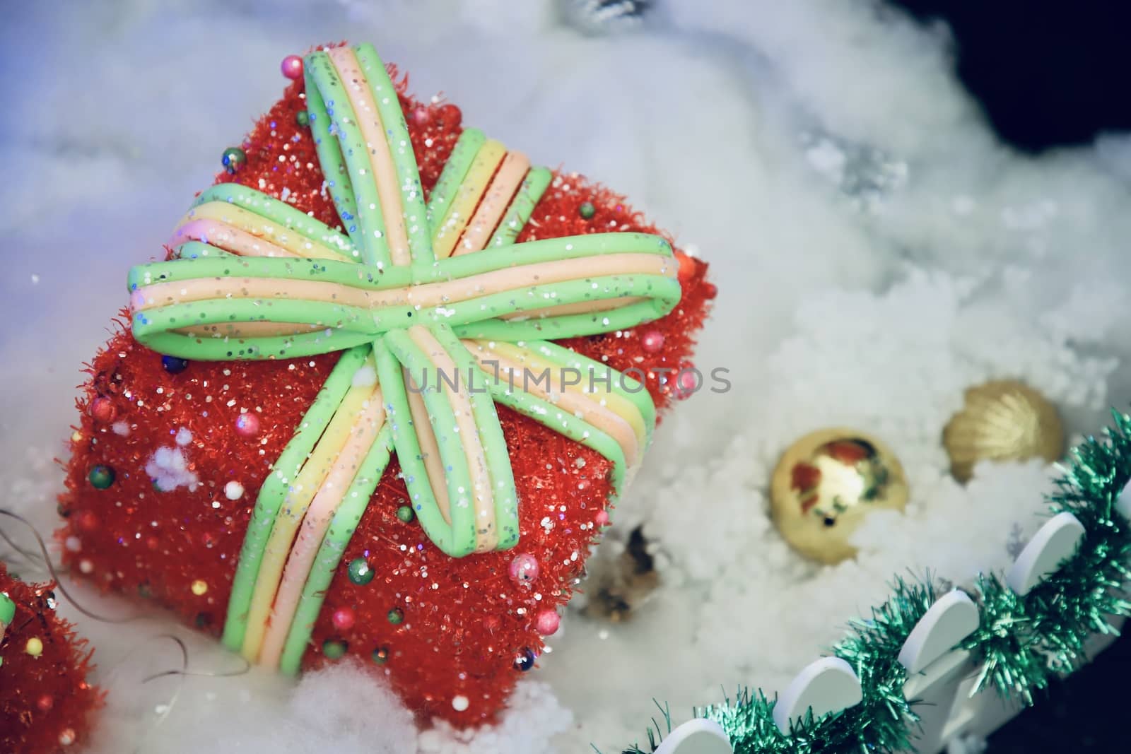 A red gift box with a green bow on a white cotton floor For decorating the New Year's venue There is space to put text. Selective focus.