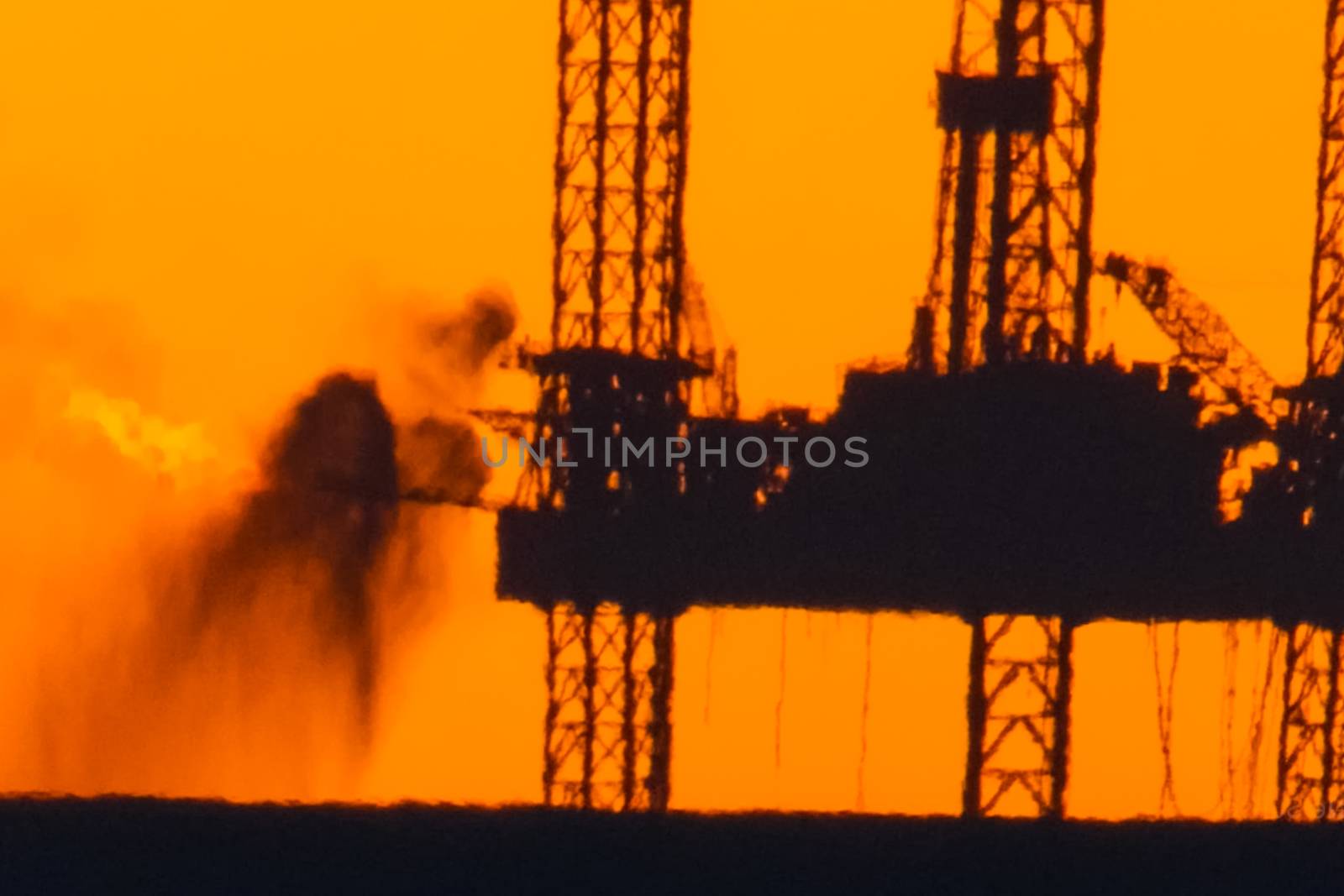 Oil platform at sunset with a burning torch.Towing of the oil platform. Drilling platform in the port. by nyrok