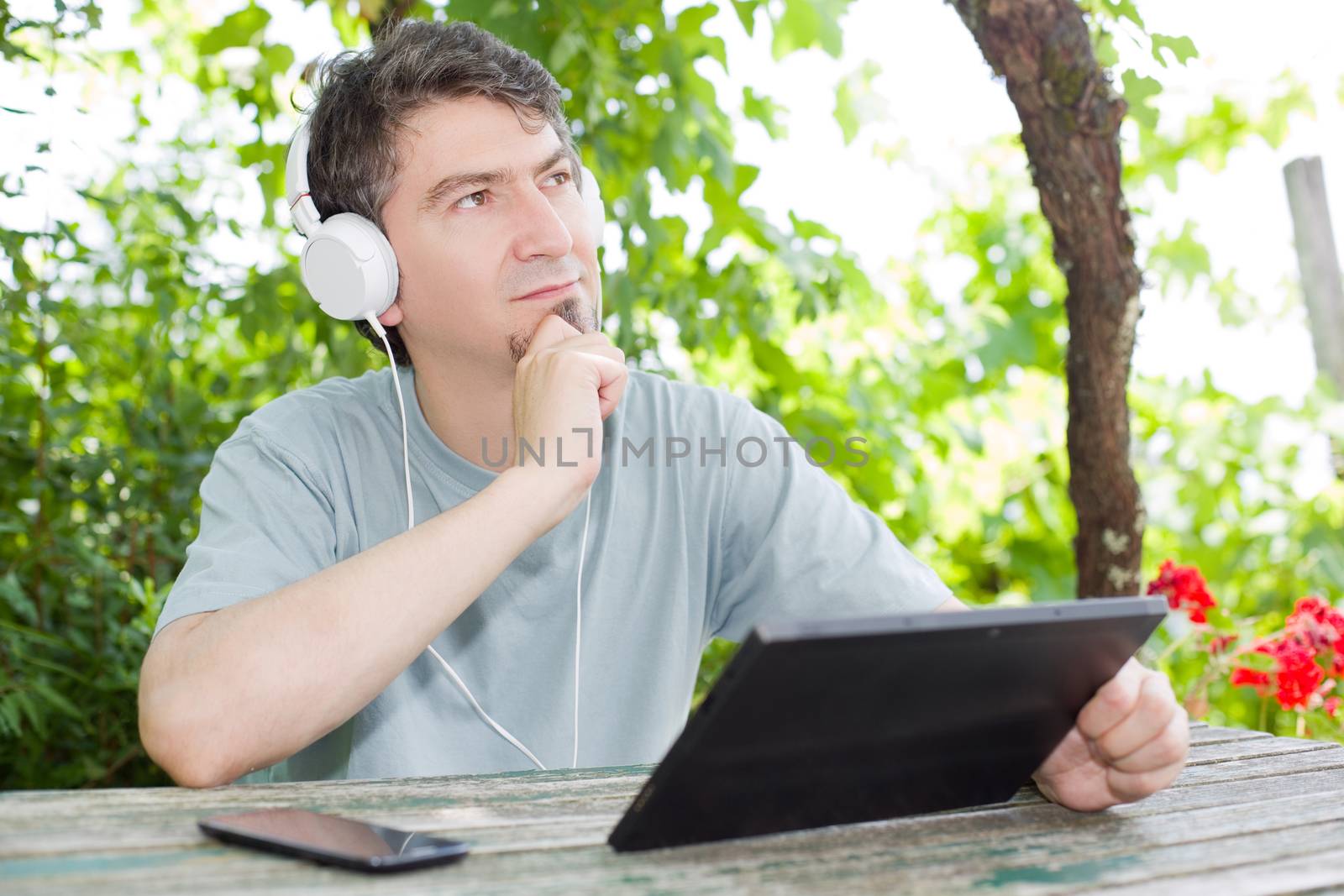 young man relaxing with a tablet pc listening music with headphones on a the park, outdoor