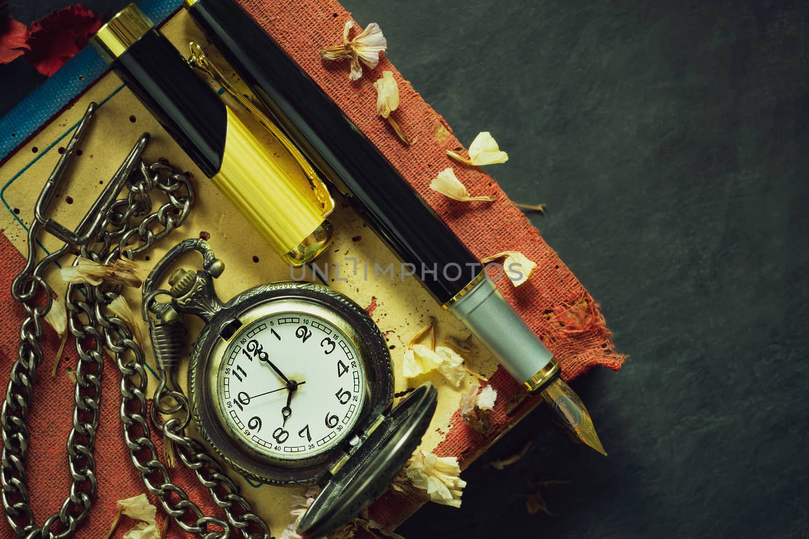 Vintage pocket watch and brass pen on old book. At 8 o’clock in morning. Top view and copy space. Education and vintage style concept.