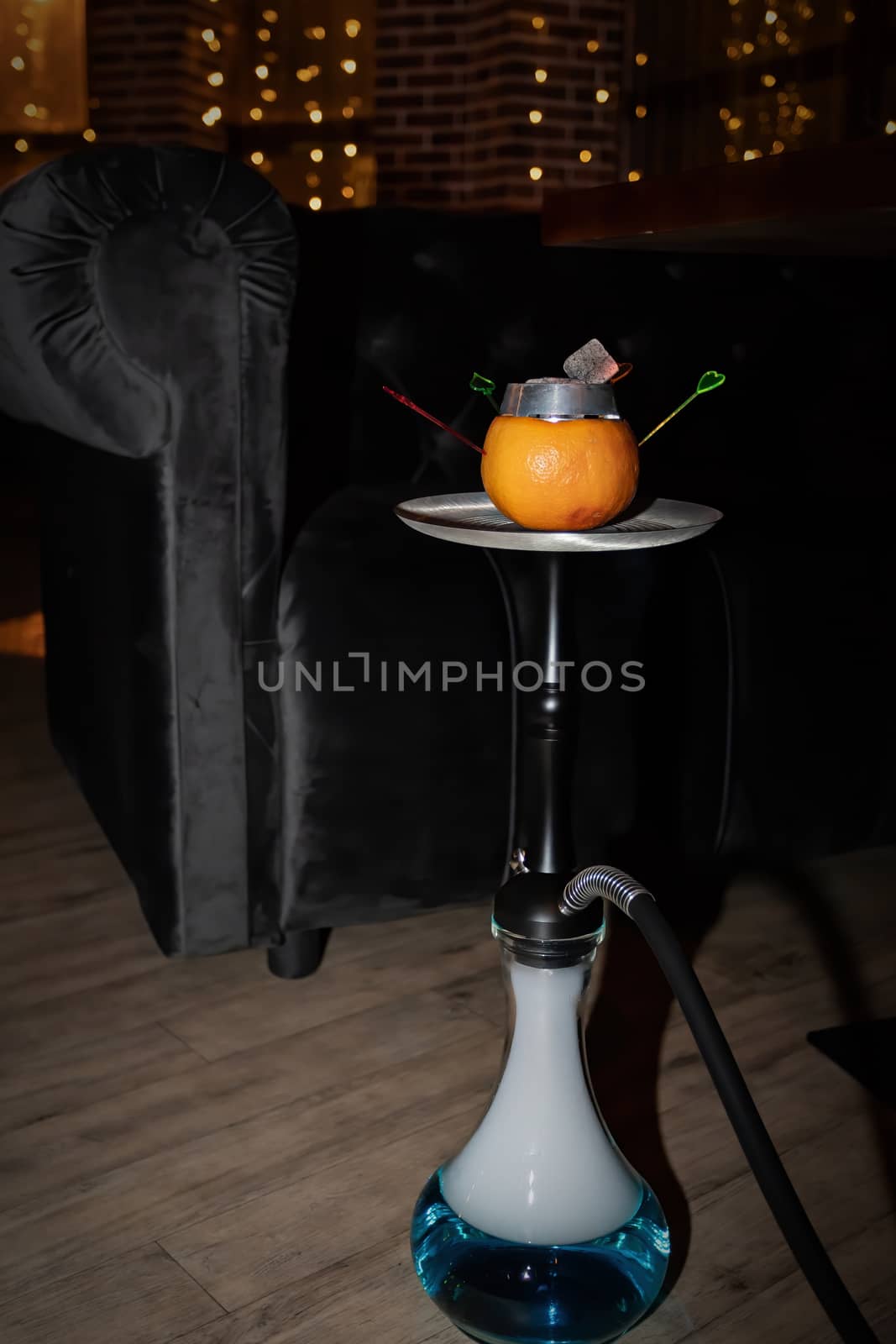 Oriental hookah with orange stands on the floor against the background of lighting in a cafe. by bonilook