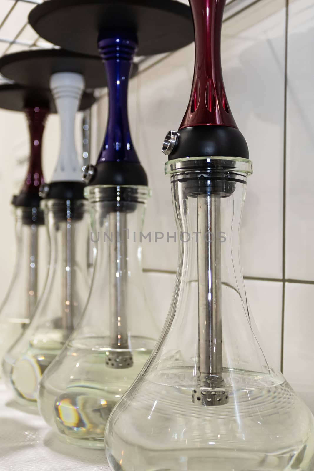 Transparent glass flasks stand in rows prepared for making a hookah. by bonilook