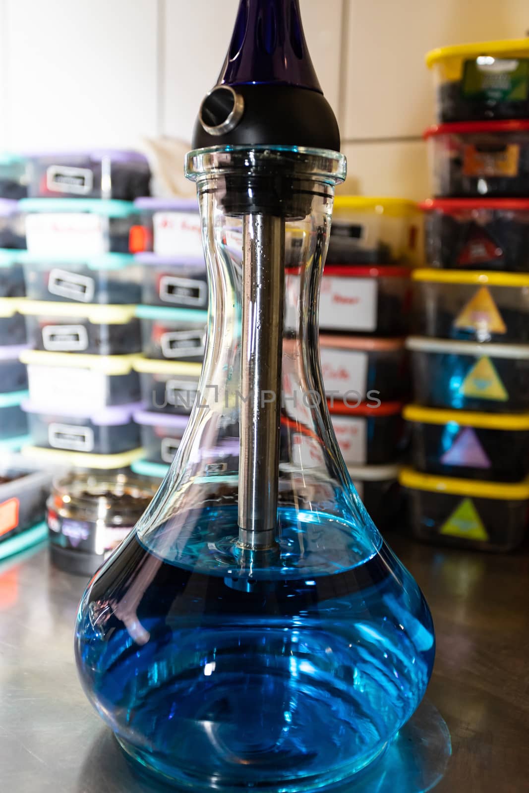 A transparent glass flask filled with blue water, the process of making a hookah. Selective focus. Close-up.