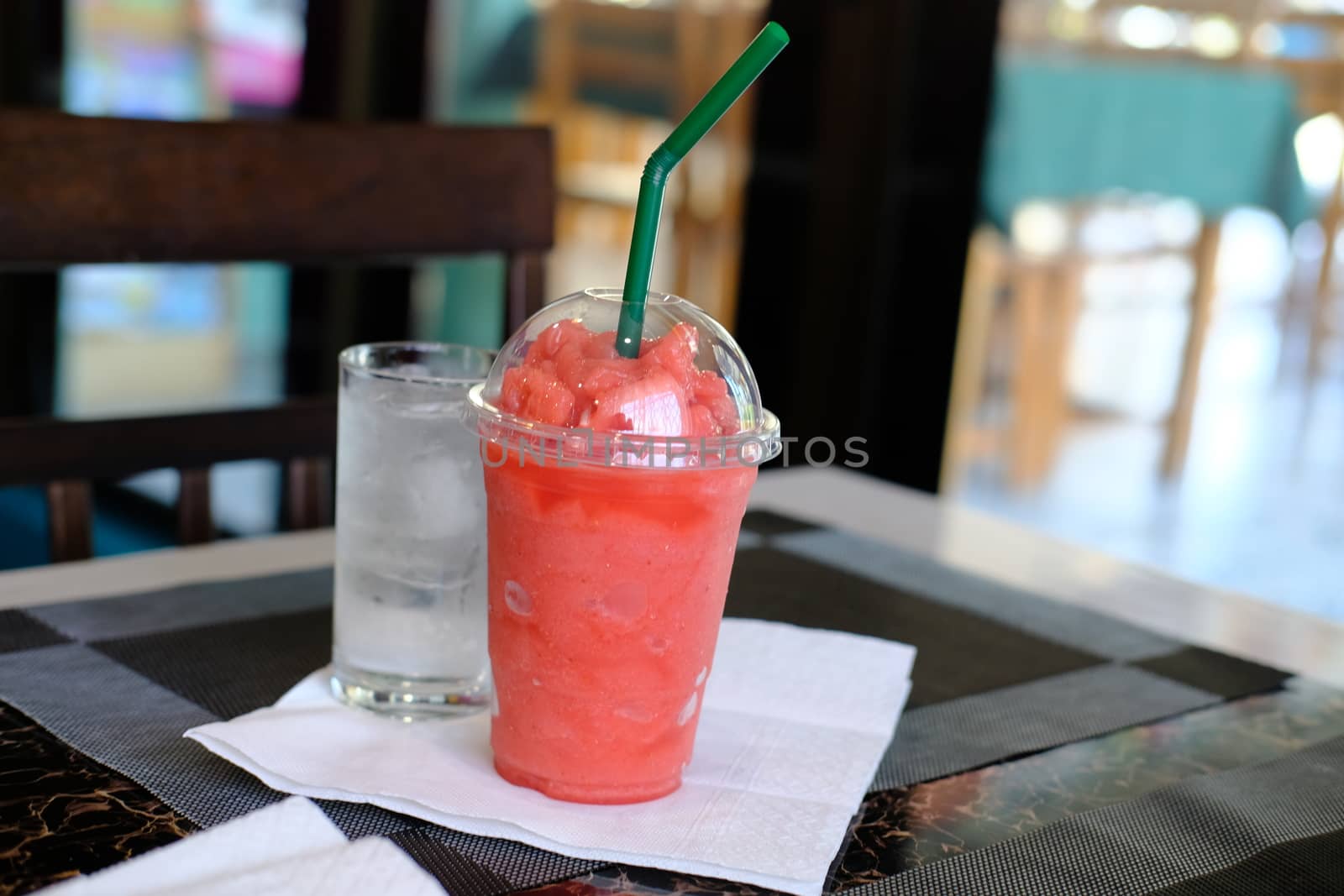 Close-up of Smoothies of watermelon frozen drink in plastic cup and glass of water. 