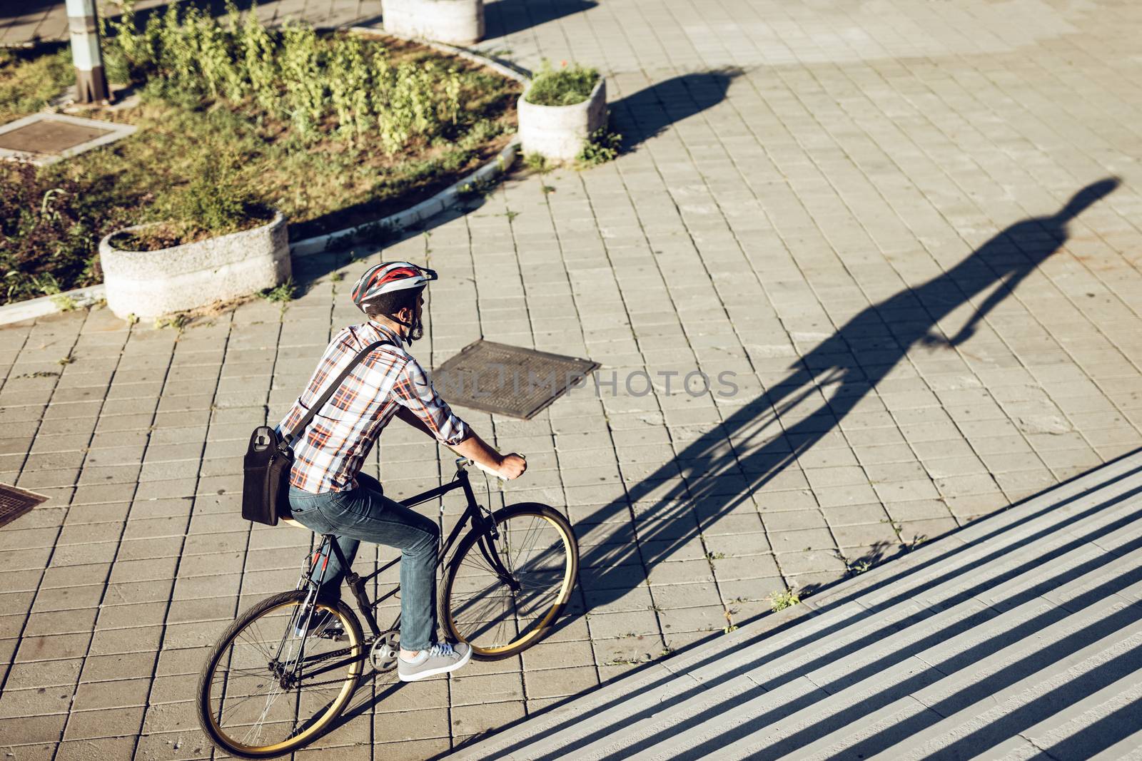 Casual handsome businessman with a helmet going to work by bicycle.