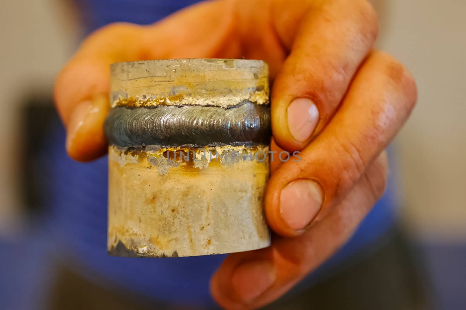 Metal pipe with a welded seam In the hand of a welder's man