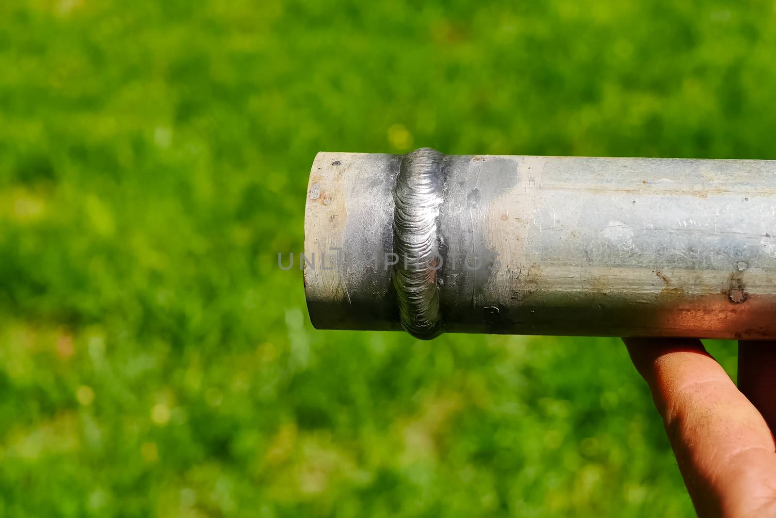 Metal pipe with a welded seam In the hand of a welder's man