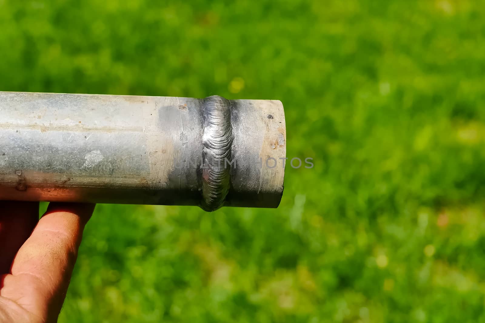 Metal pipe with a welded seam In the hand of a welder's man