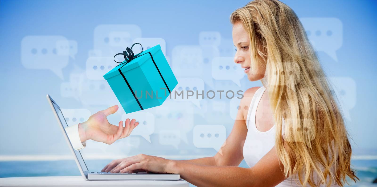 Composite image of pretty blonde using her laptop at the beach with hand presenting gift