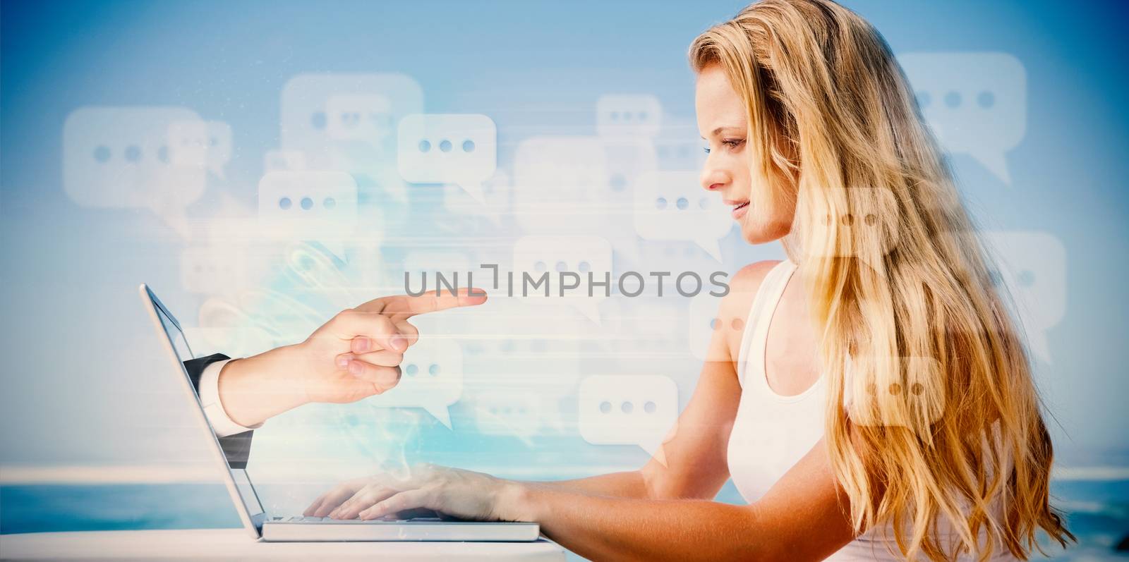 Composite image of pretty blonde using her laptop at the beach with hand pointing
