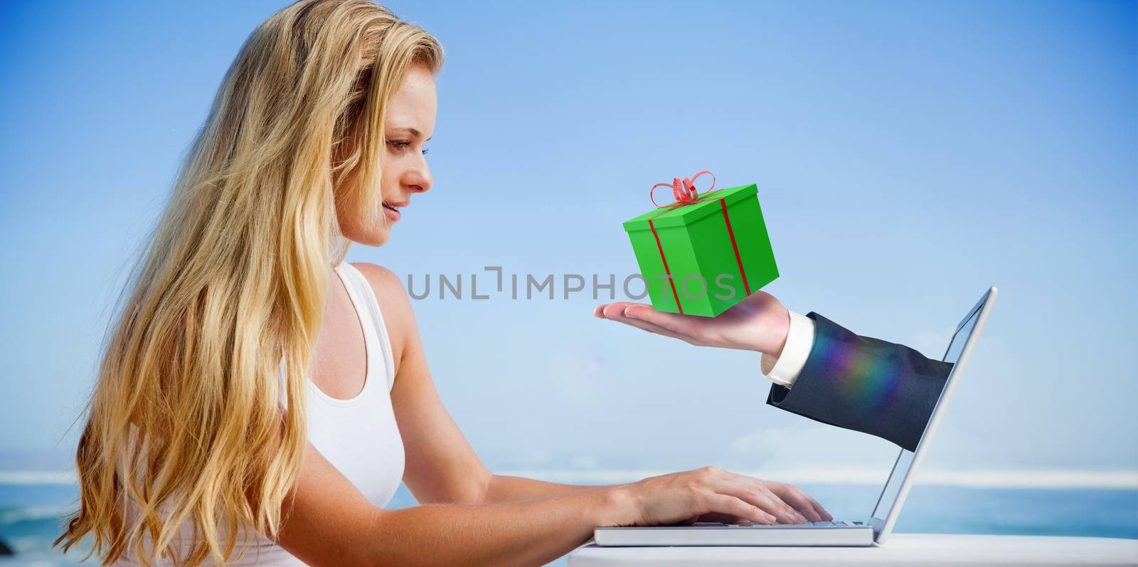 Composite image of pretty blonde using her laptop at the beach with hand presenting