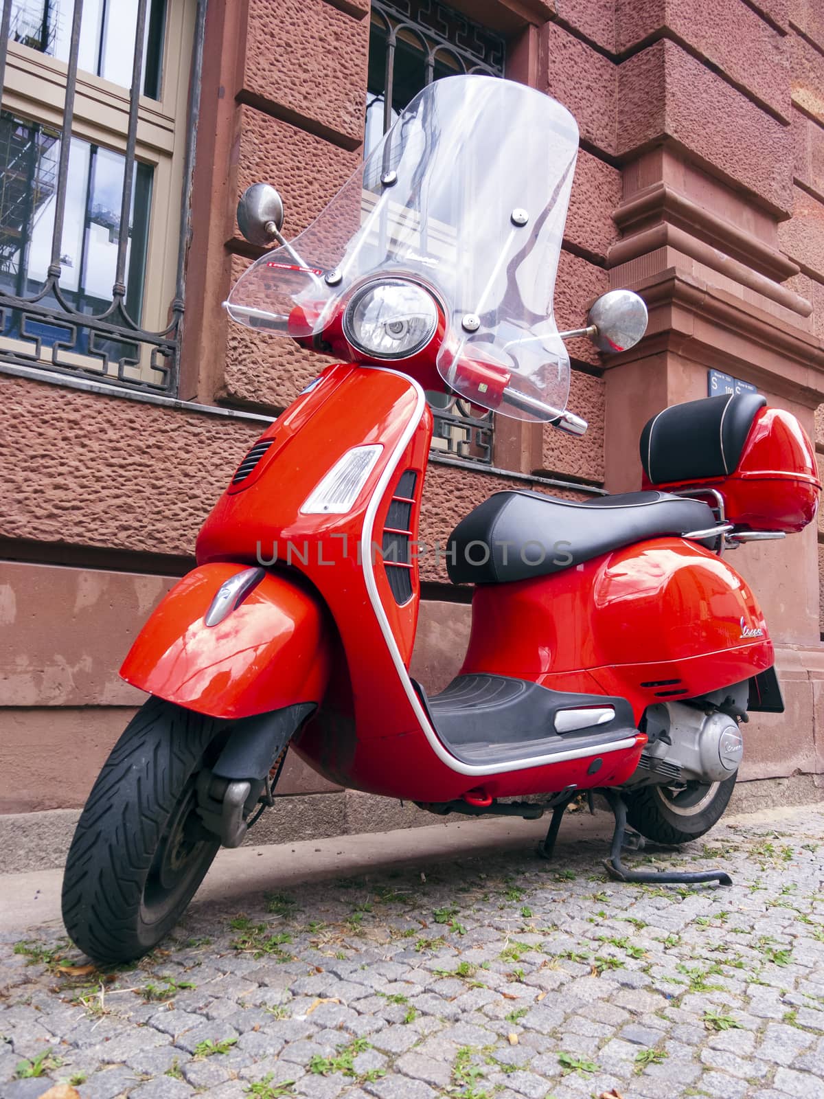 Berlin, Germany - August 13, 2019: A red Vespa stands on the edge of the road in Berlin