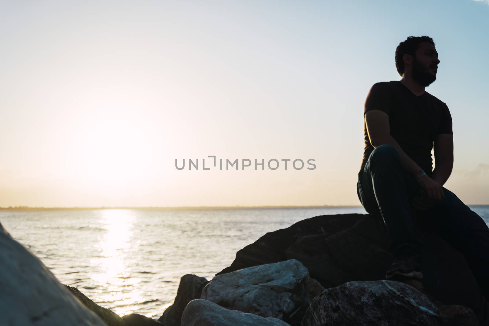 Man sitting and relaxing in a rock looking at the sea by henrry08